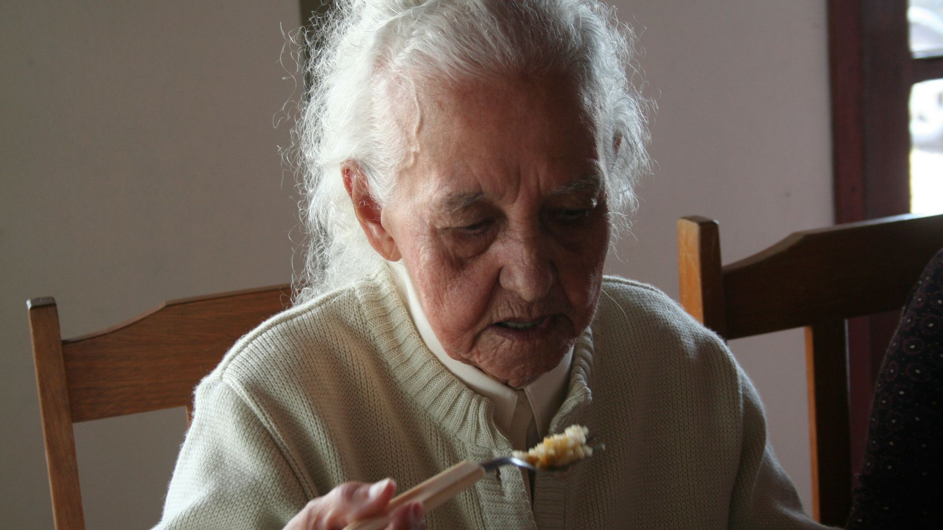 man in white sweater holding fork