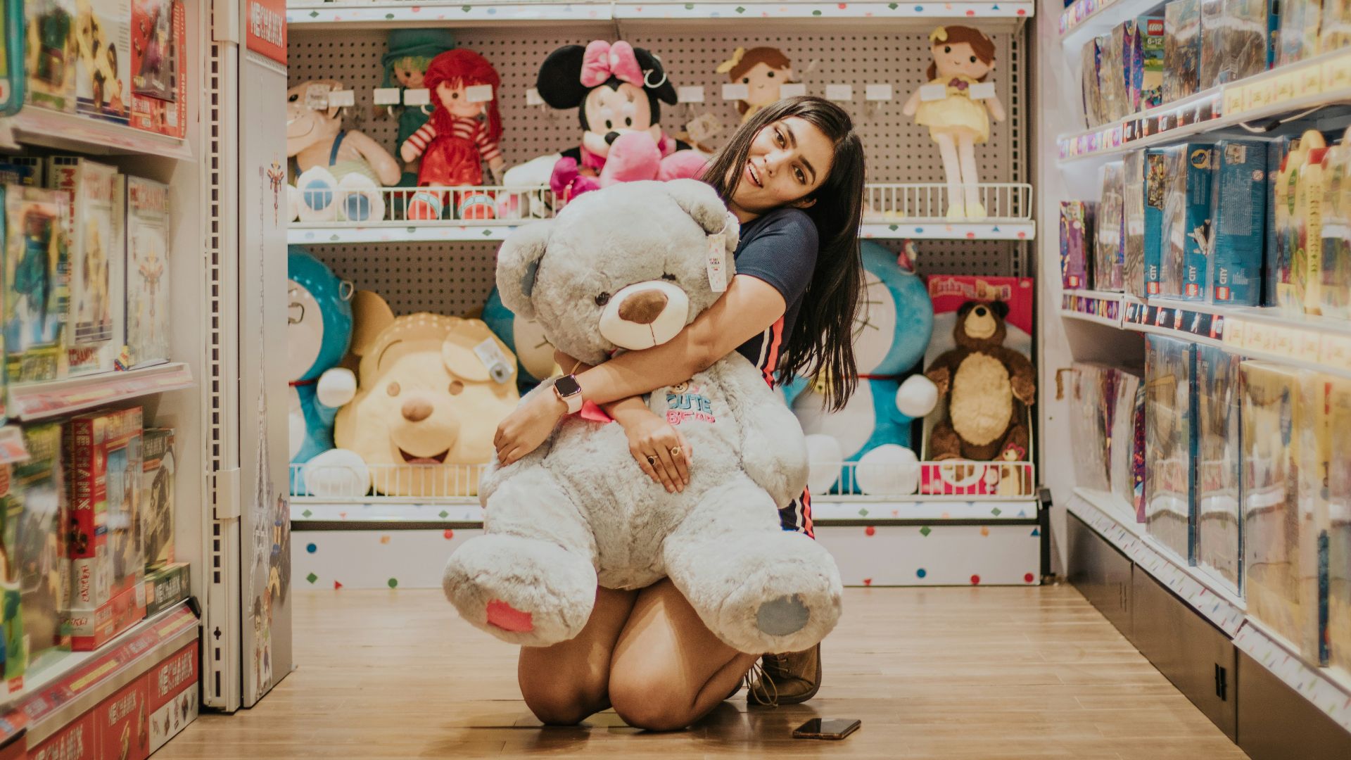 woman in black shirt sitting beside white bear plush toy