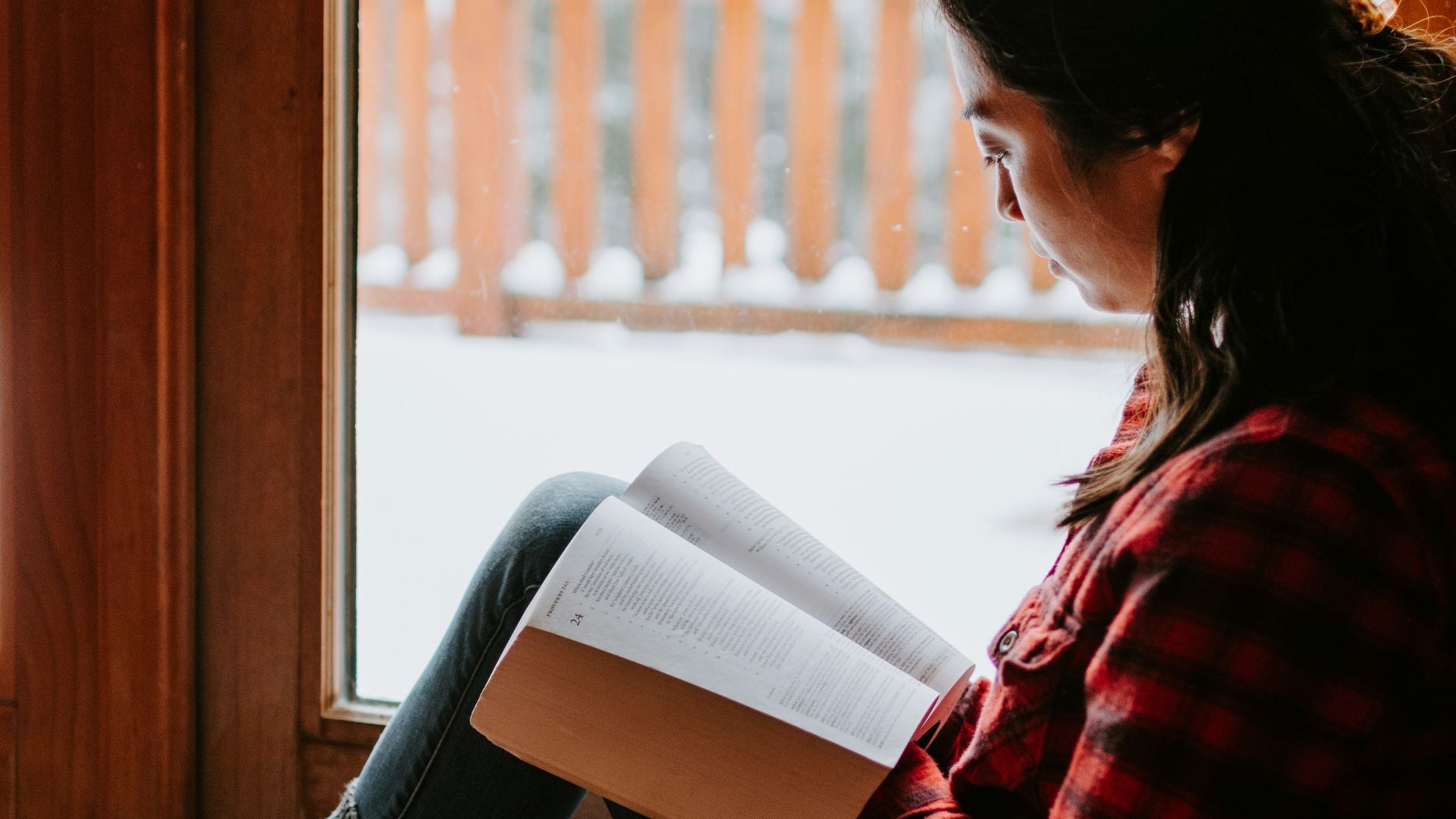 woman in red and black striped long sleeve shirt and blue denim jeans sitting on brown