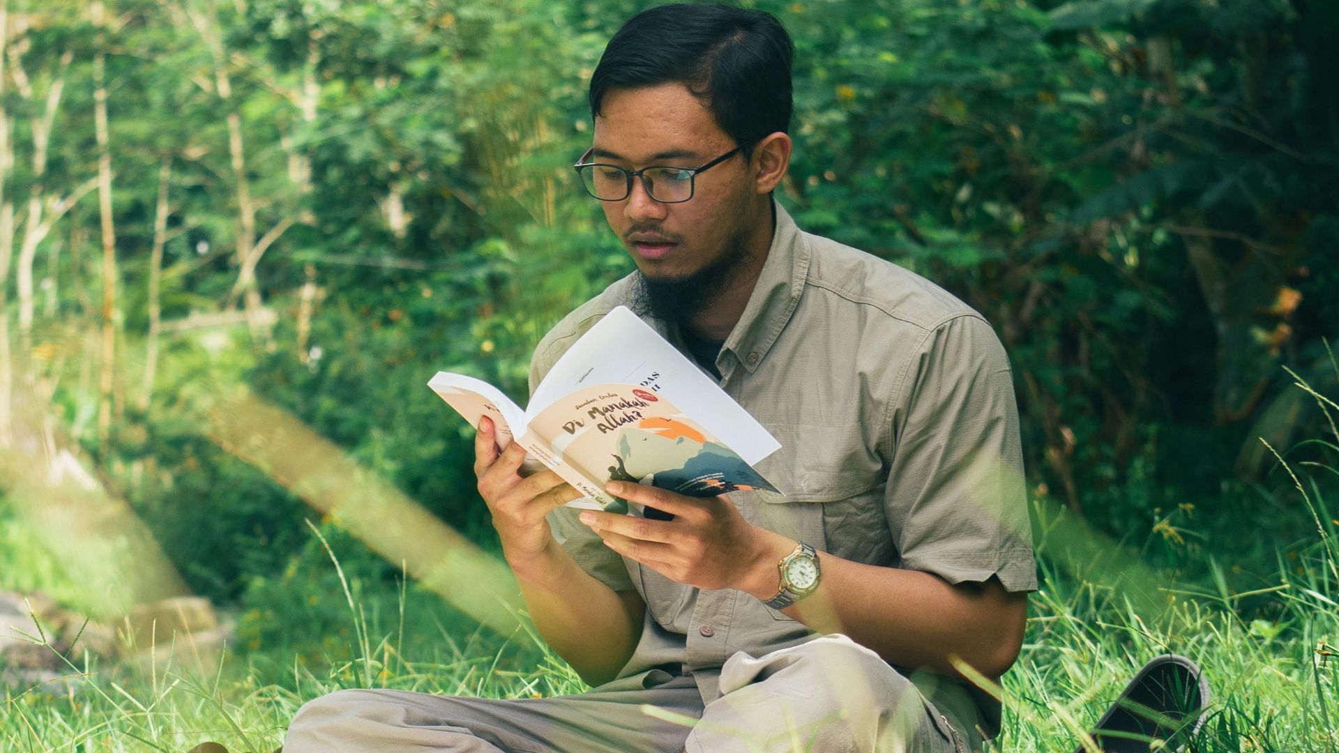 a man sitting in the grass reading a book