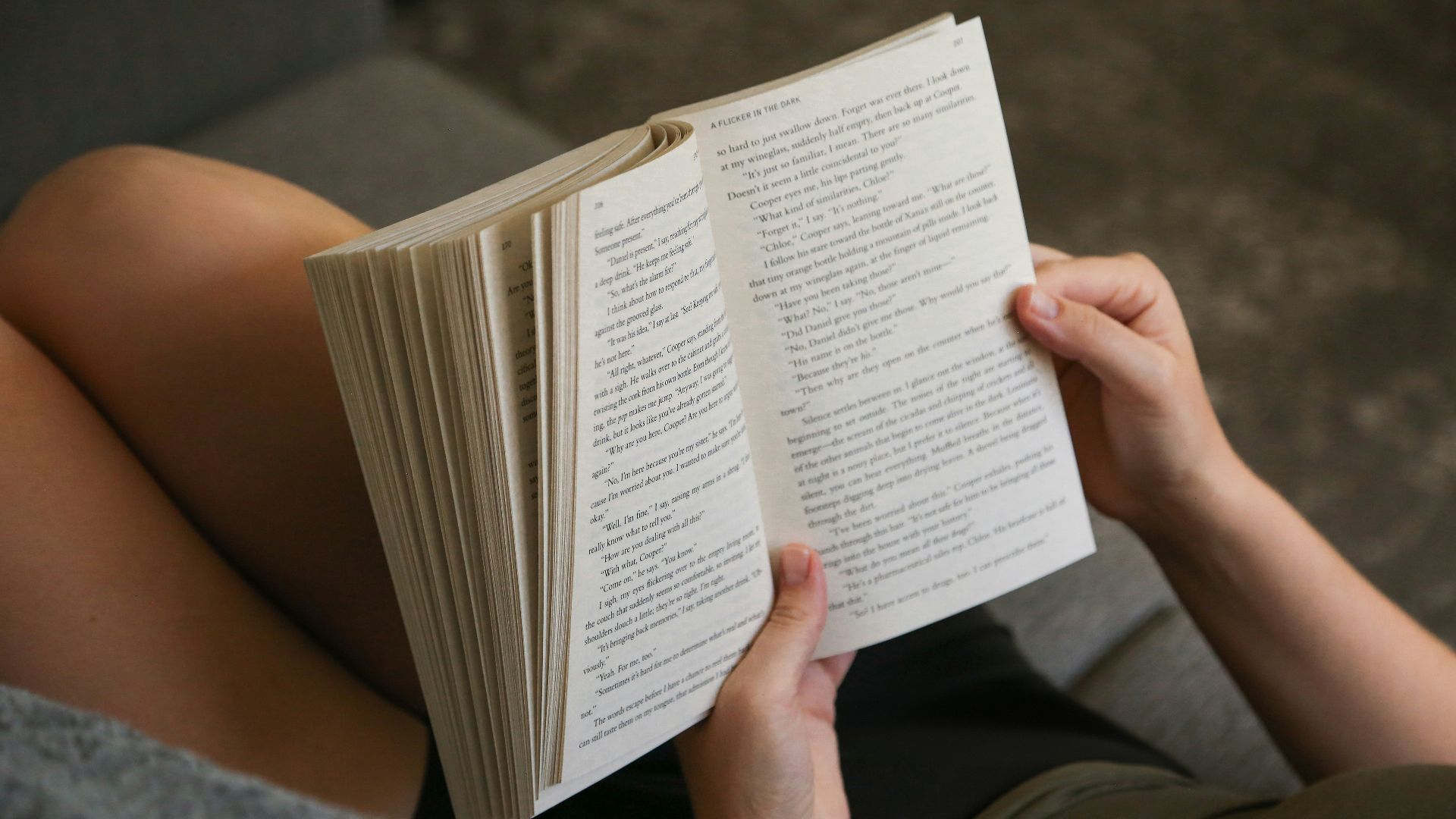 A person laying on a couch reading a book