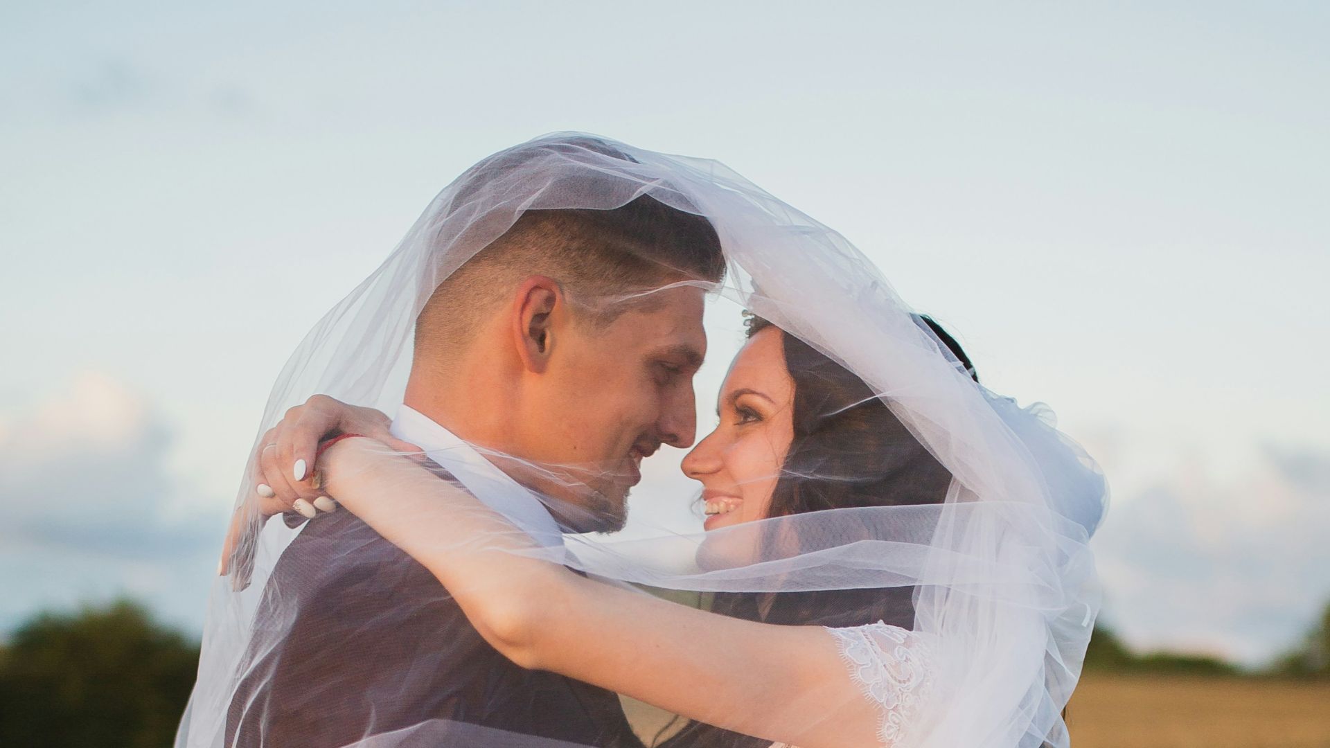smiling newly wed couple about to kiss in green field