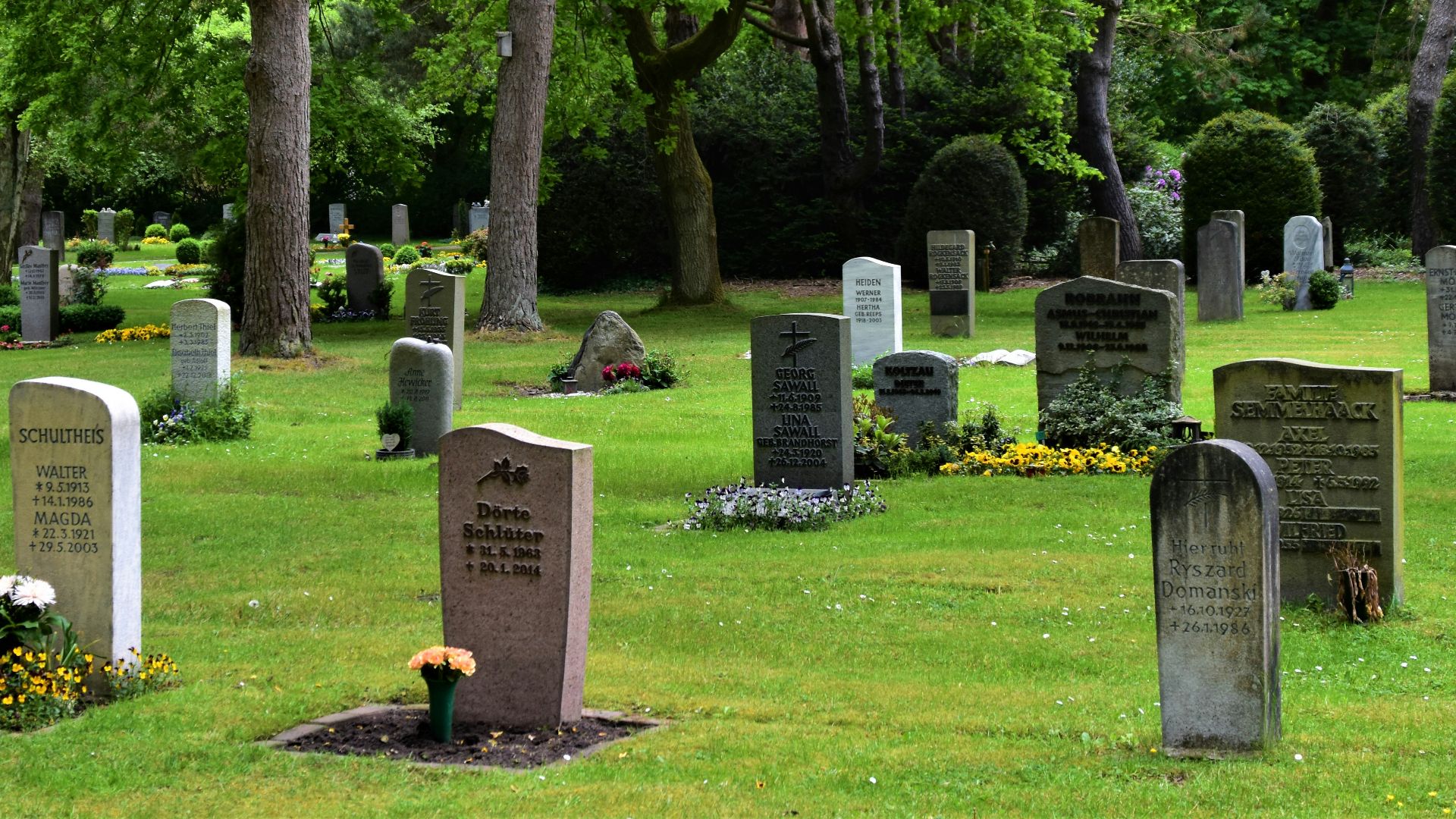 gray concrete cross on green grass field during daytime