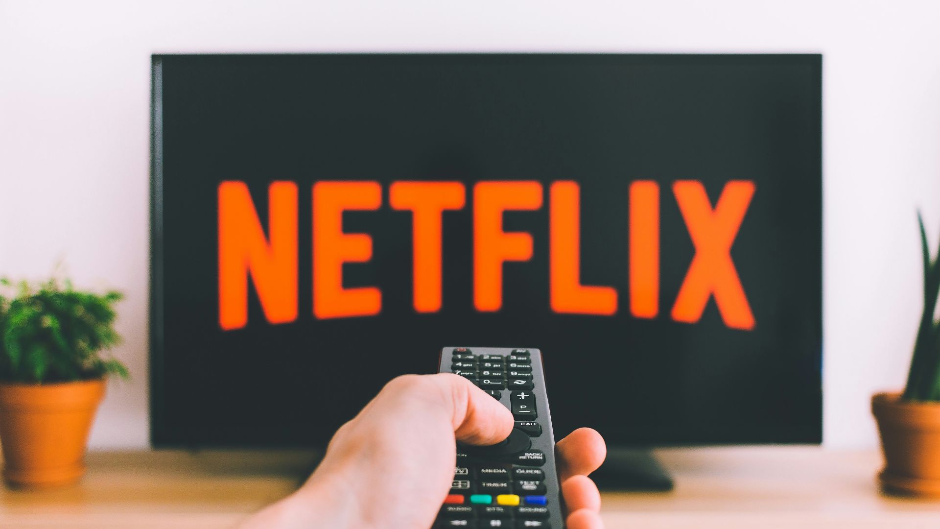 person holding remote pointing at TV