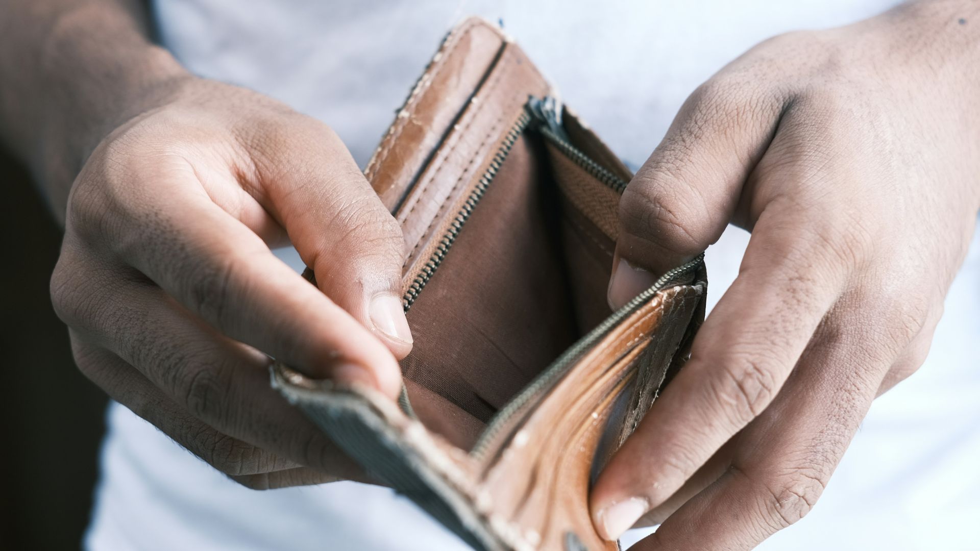 person holding brown leather bifold wallet