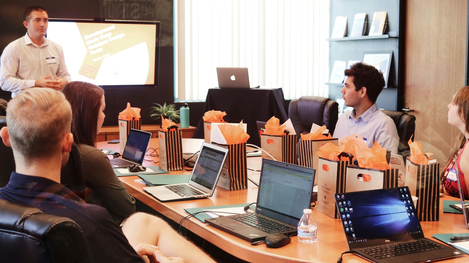 man standing in front of people sitting beside table with laptop computers