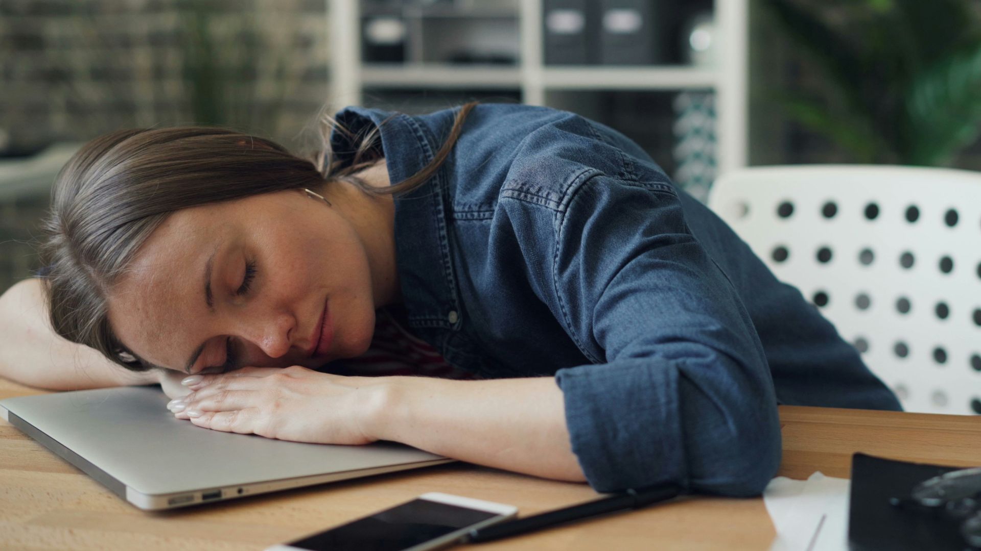 a woman laying her head on a laptop