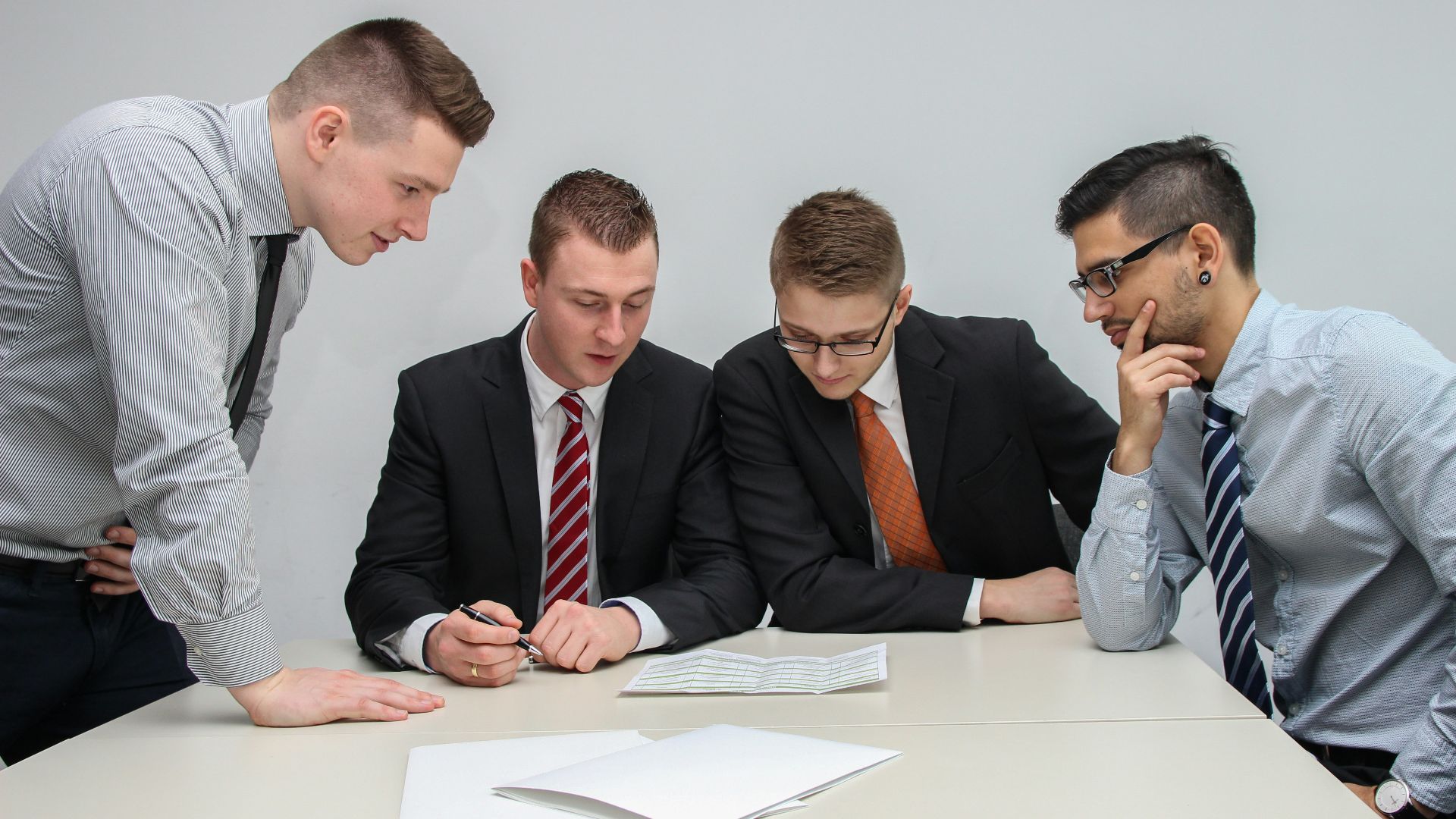 four men looking to the paper on table