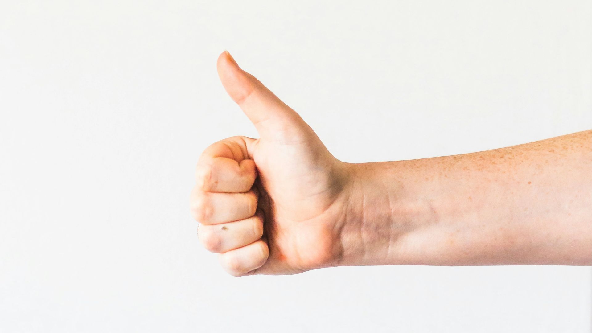 persons right hand doing thumbs up