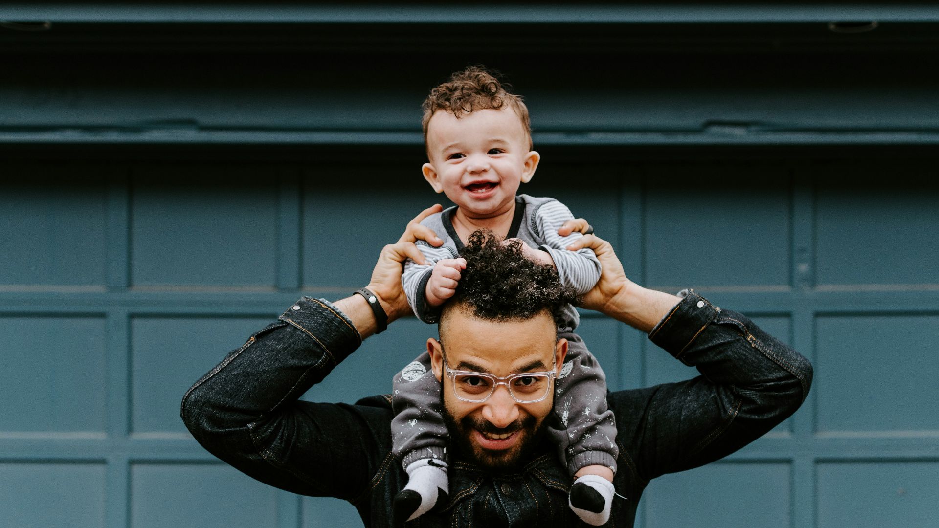 man in black leather jacket carrying boy in black leather jacket