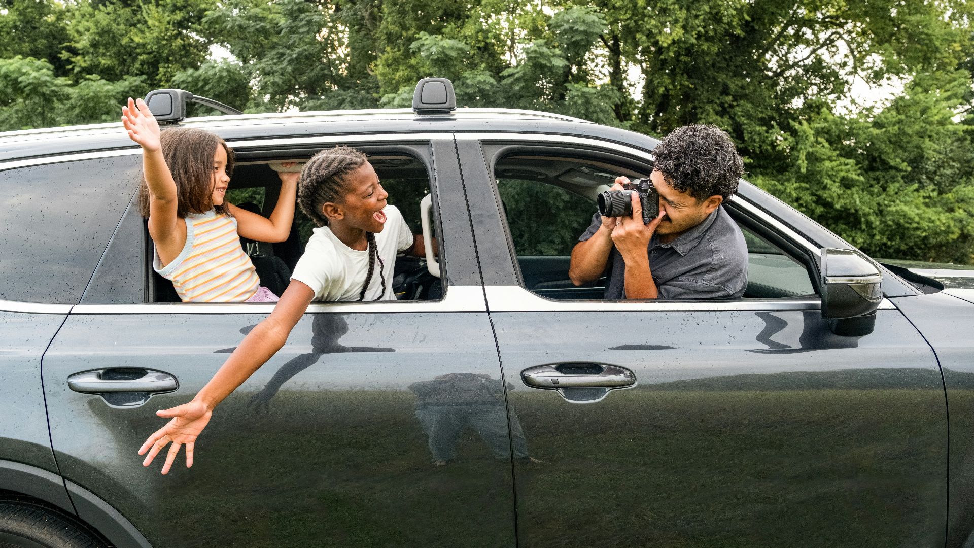 Man photographs children leaning out of car window