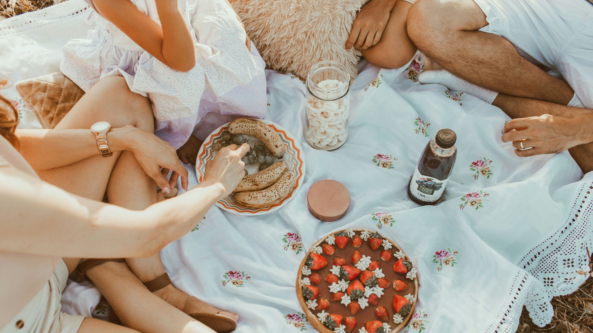 people sitting on white textile eating bread near cake