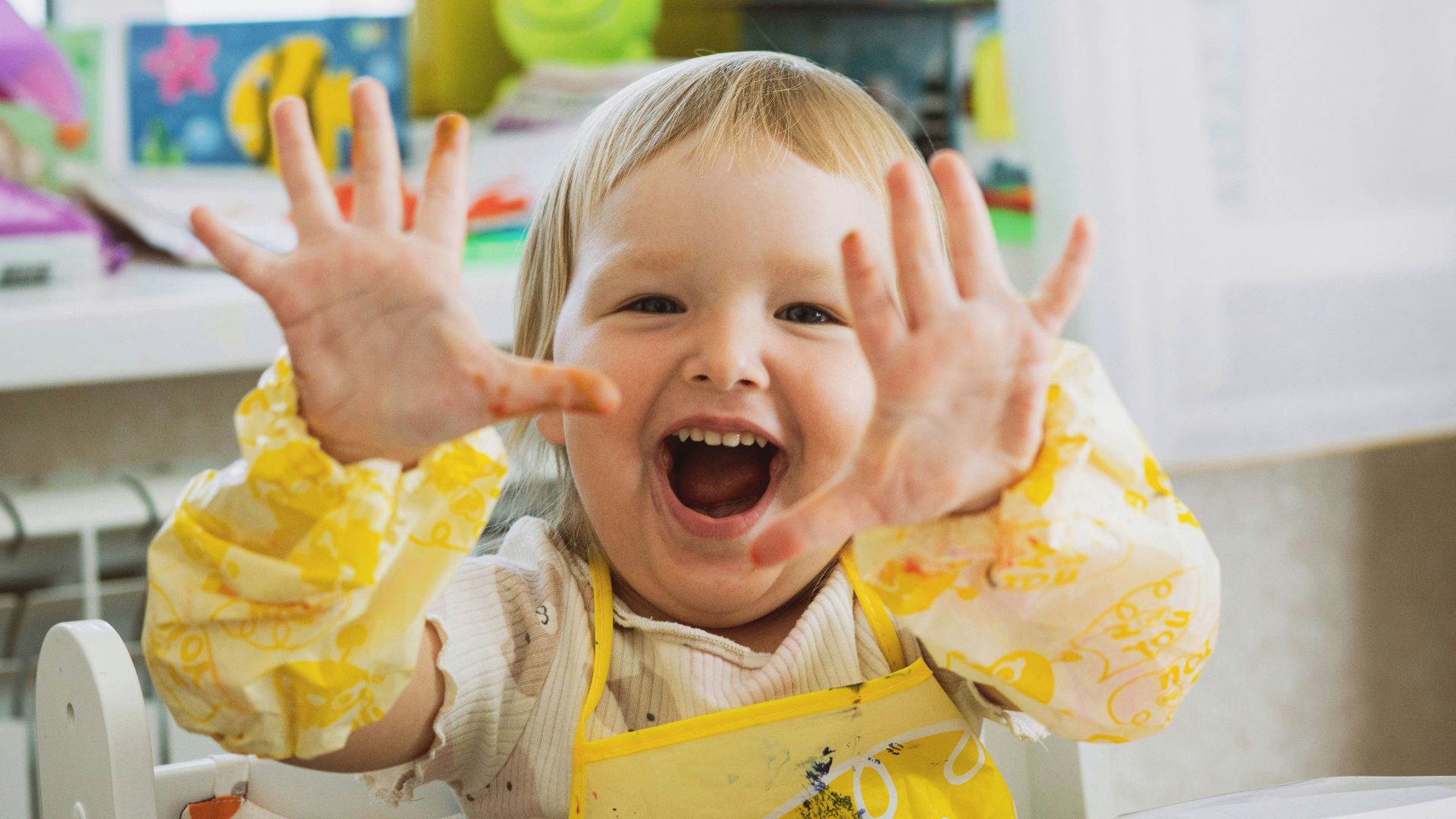 Happy child shows off colorful, messy hands.