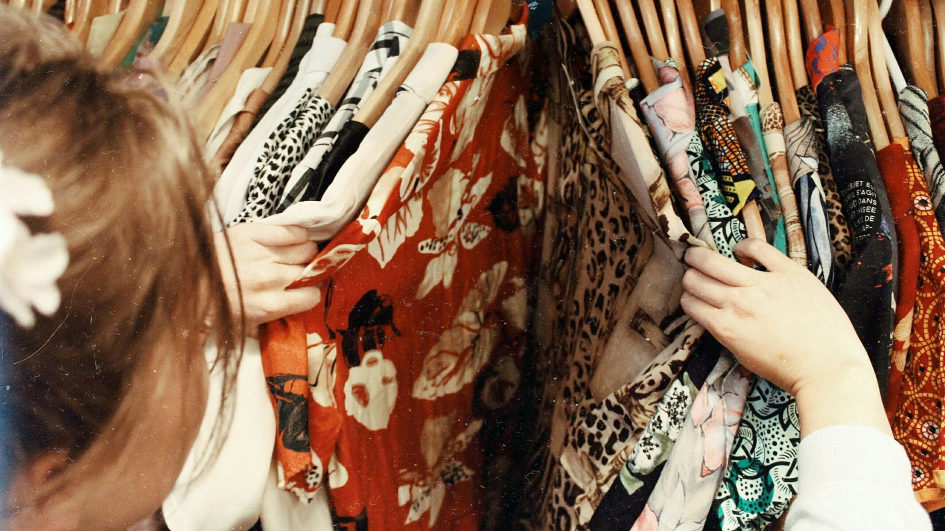 person holding assorted clothes in wooden hanger