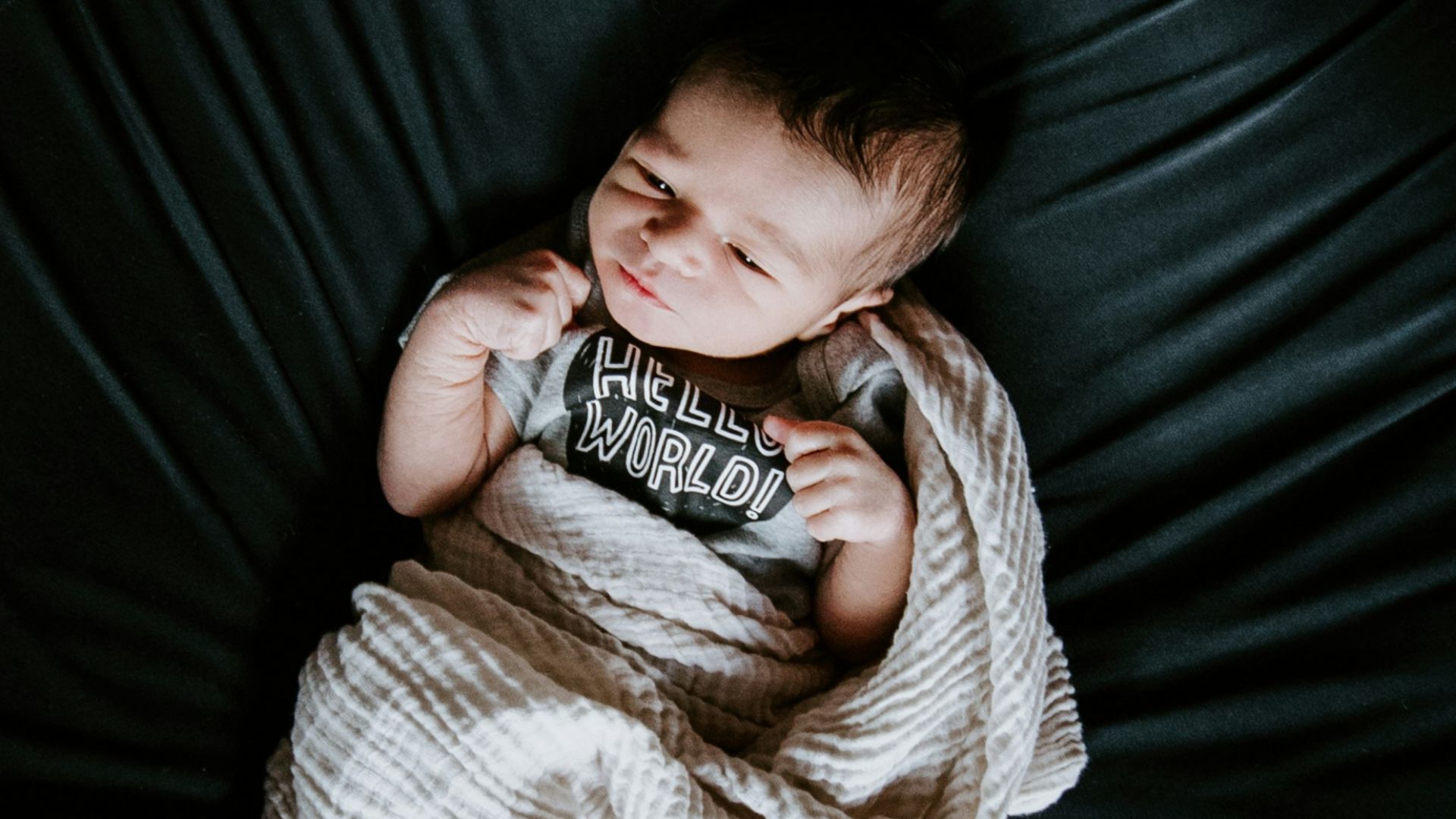 girl in white sweater and black pants lying on black round bed