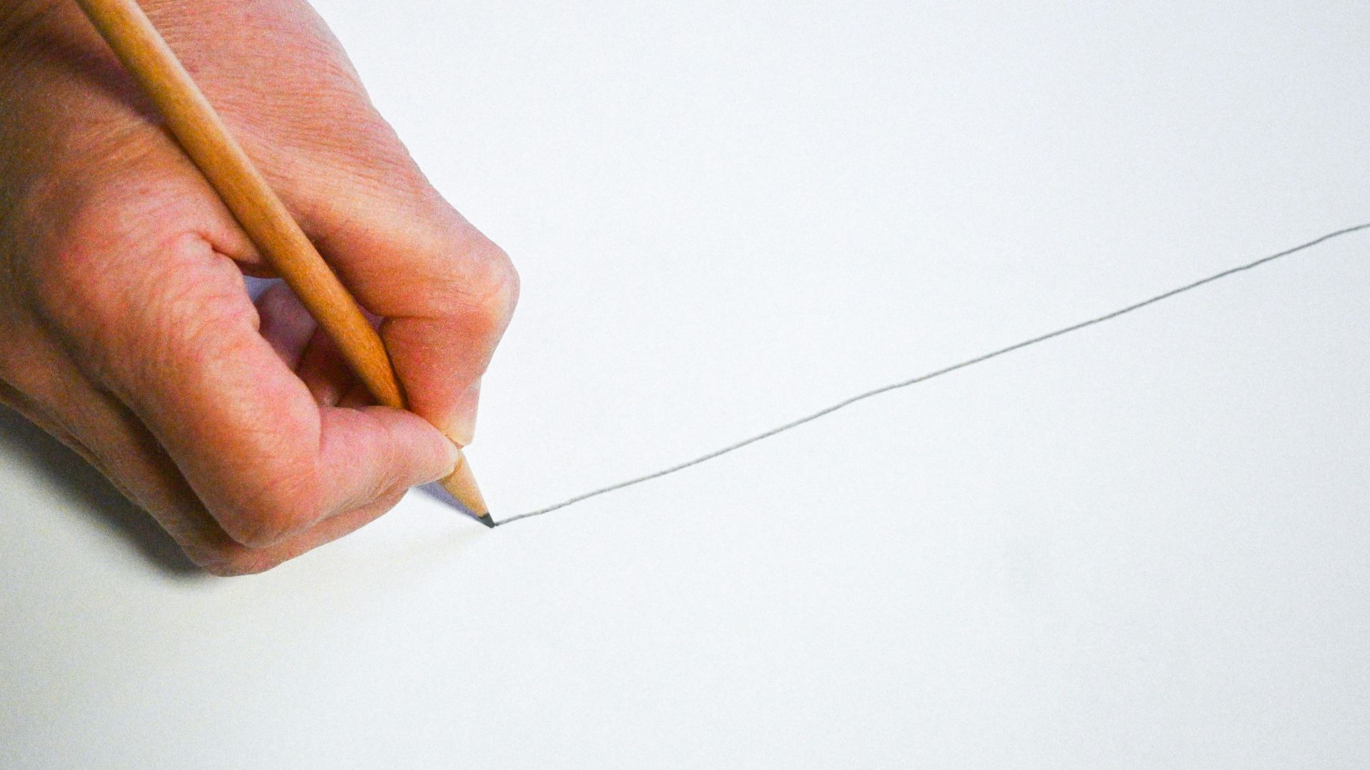 A person holding a pencil and writing on a piece of paper