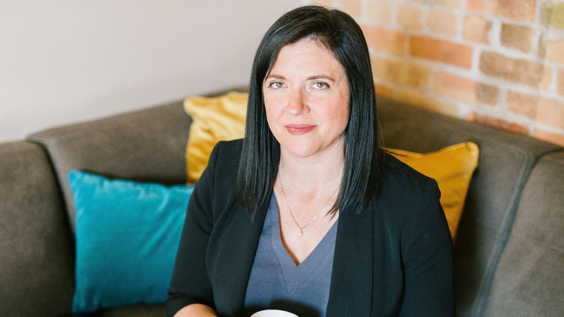 woman holding cup of coffee sitting on sofa