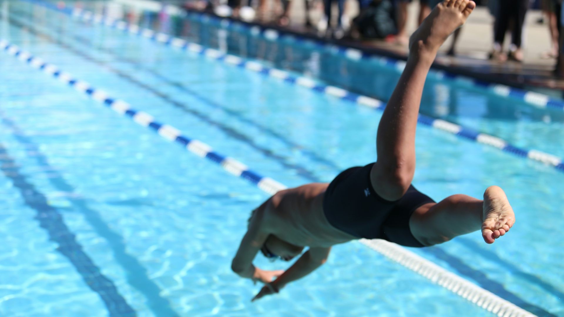 woman in black one piece swimsuit jumping on swimming pool during daytime
