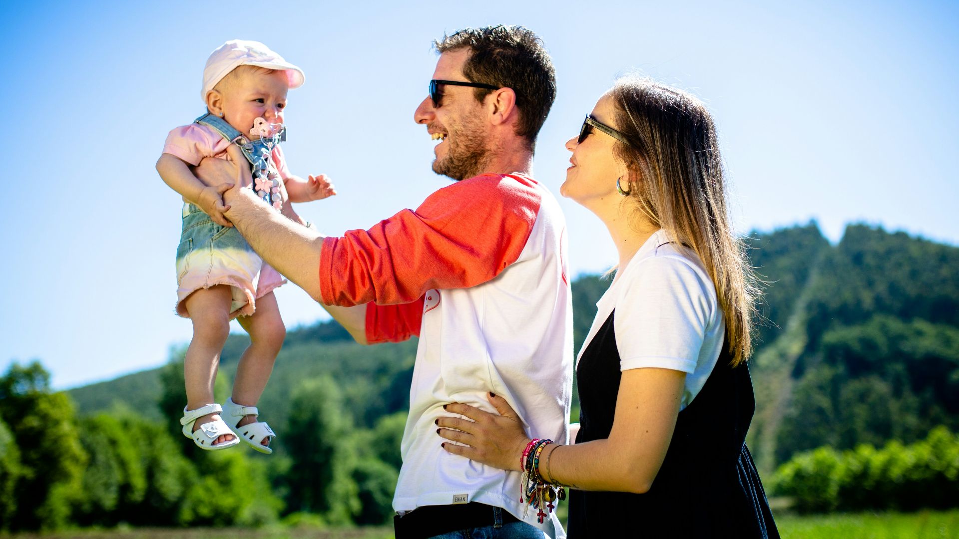 man in white and red polo shirt carrying girl in blue denim jeans during daytime