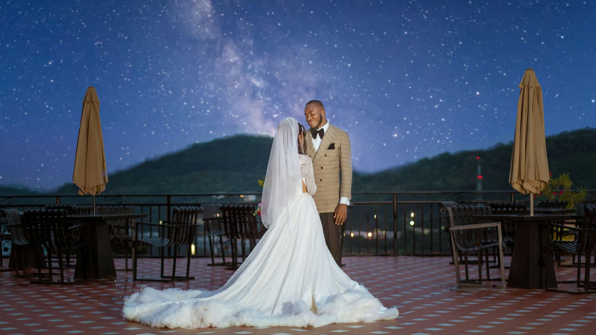 a bride and groom standing in front of a night sky