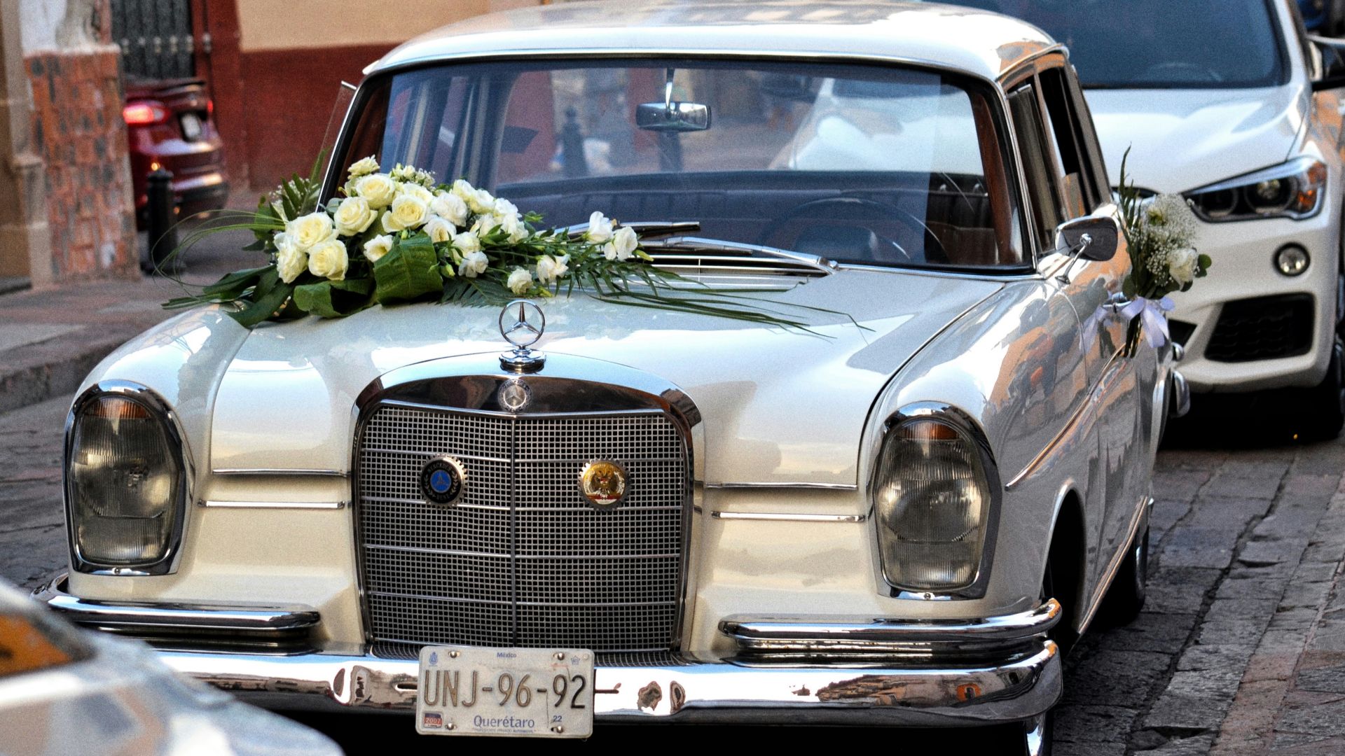 A vintage mercedes with wedding flowers is shown.