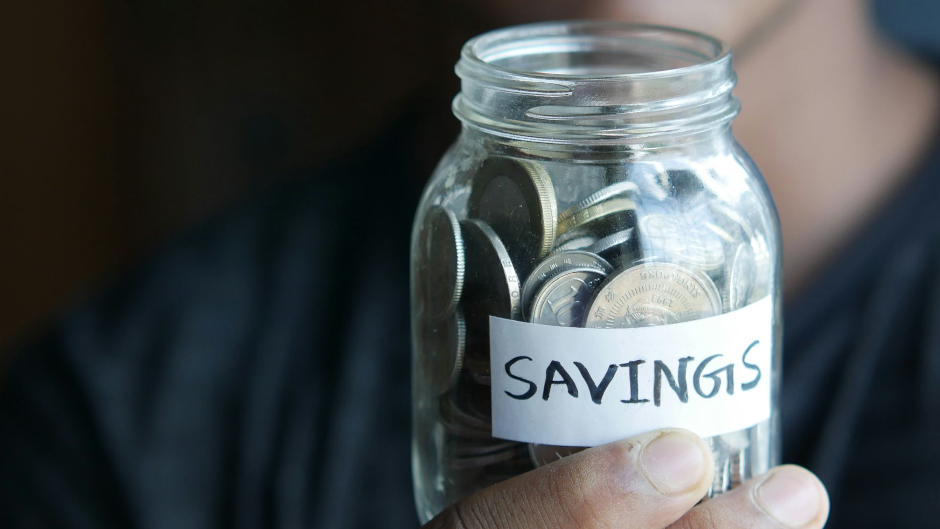 a man holding a jar with a savings label on it