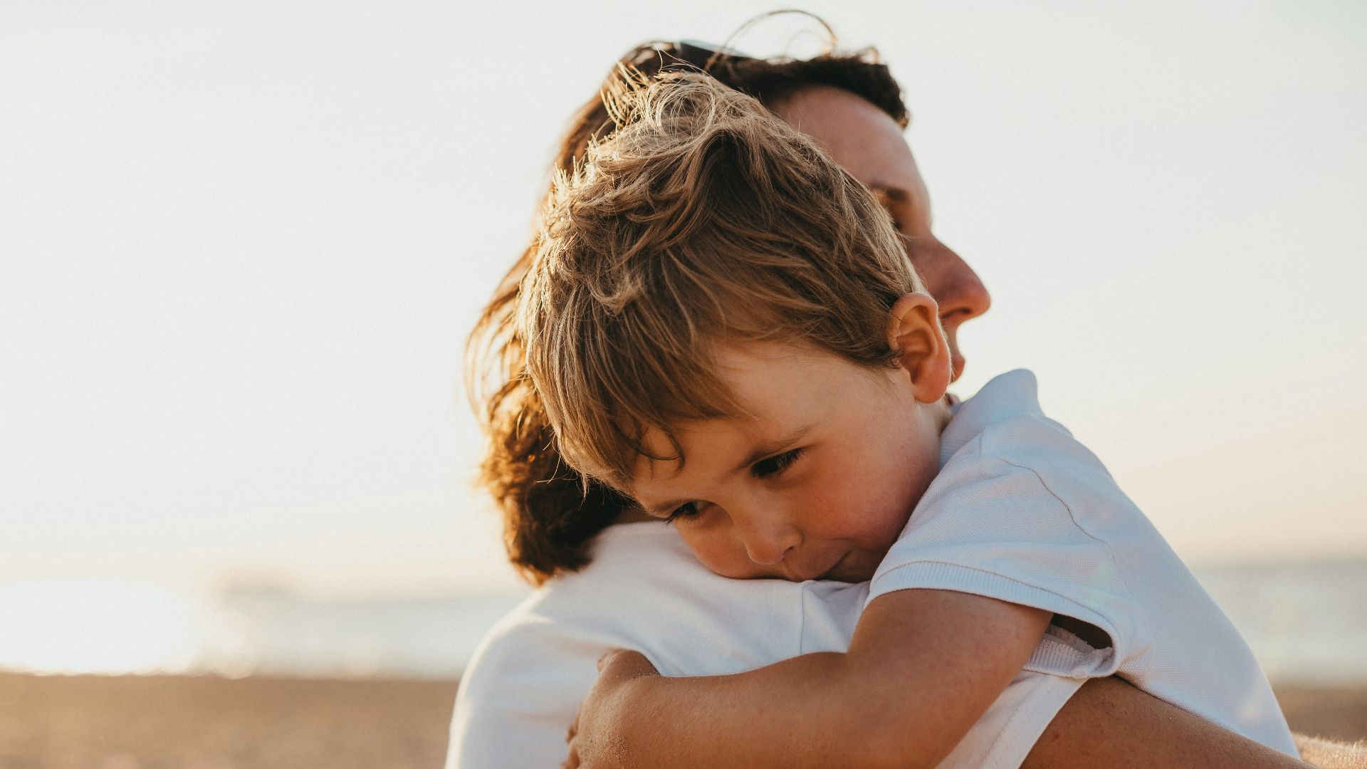 boy hugging woman during daytime