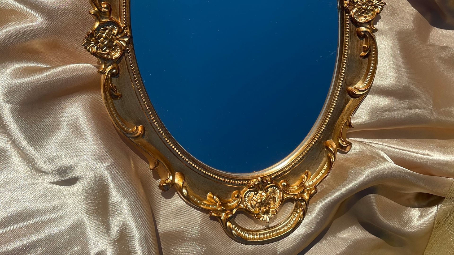a mirror sitting on top of a satin covered bed
