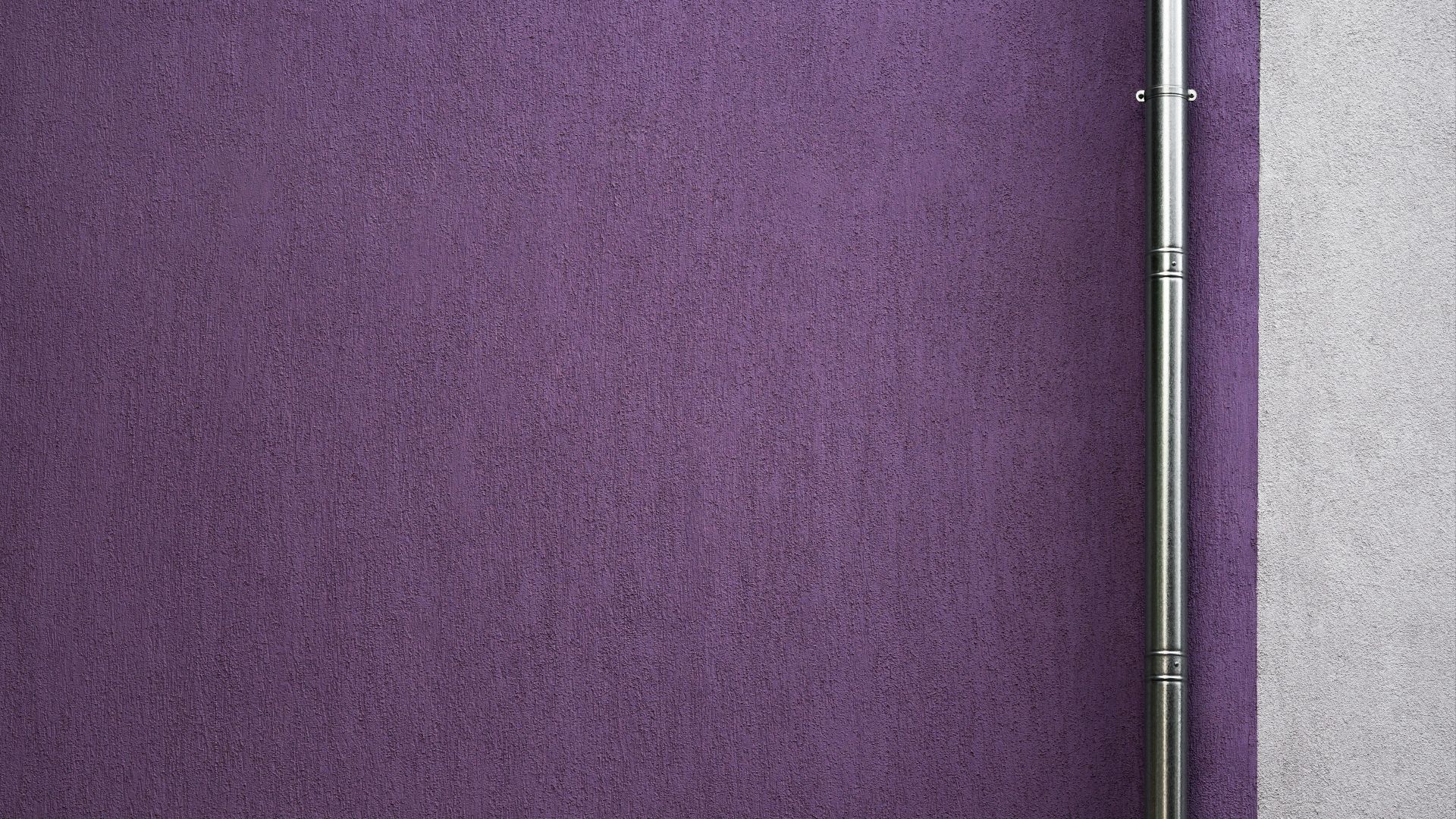 a purple wall with a metal pole on top of it