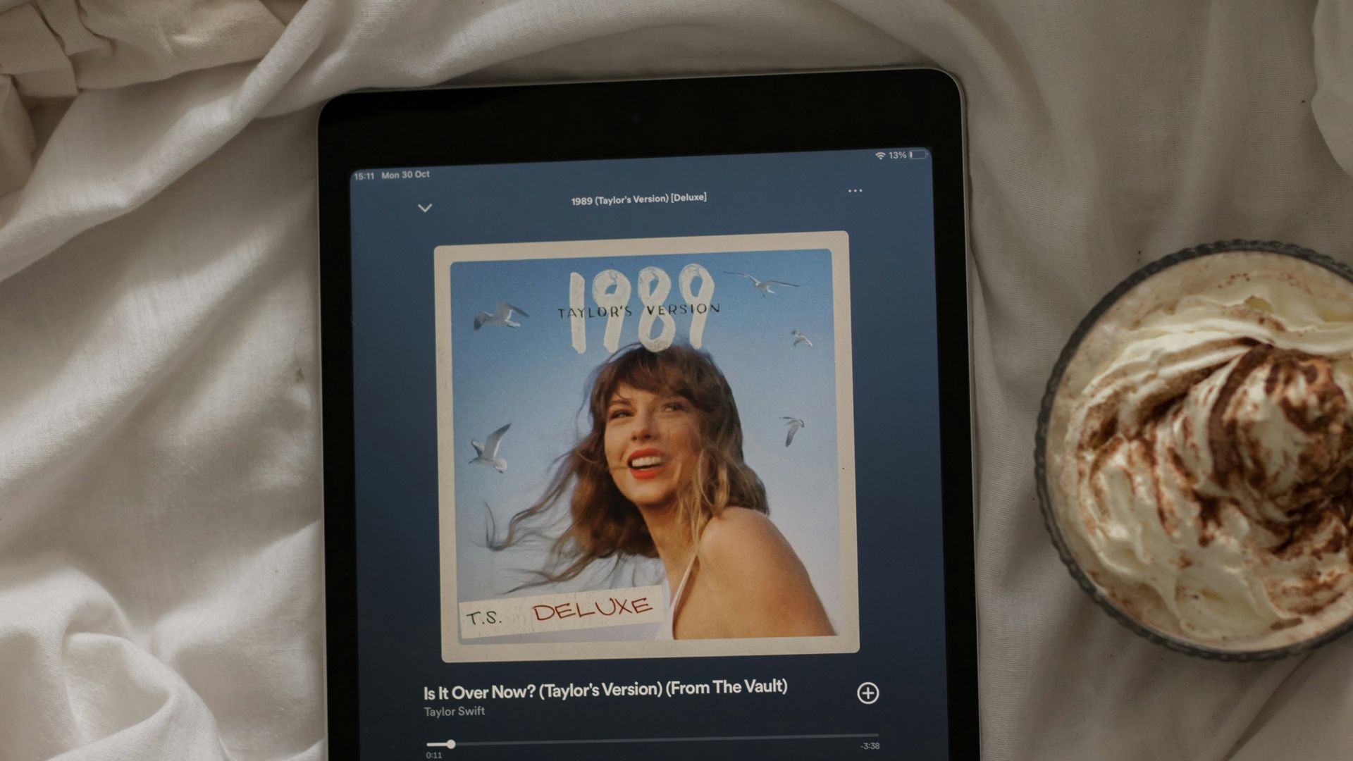 a tablet sitting on top of a bed next to a cup of coffee