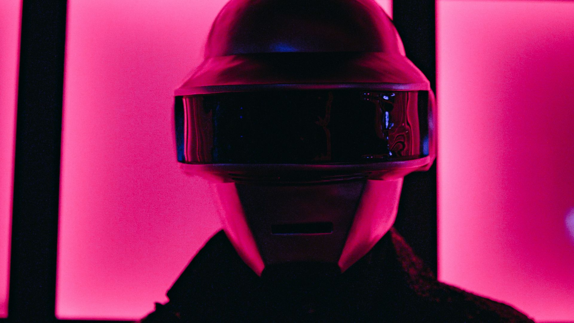a person wearing a helmet standing in front of a wall of pink squares