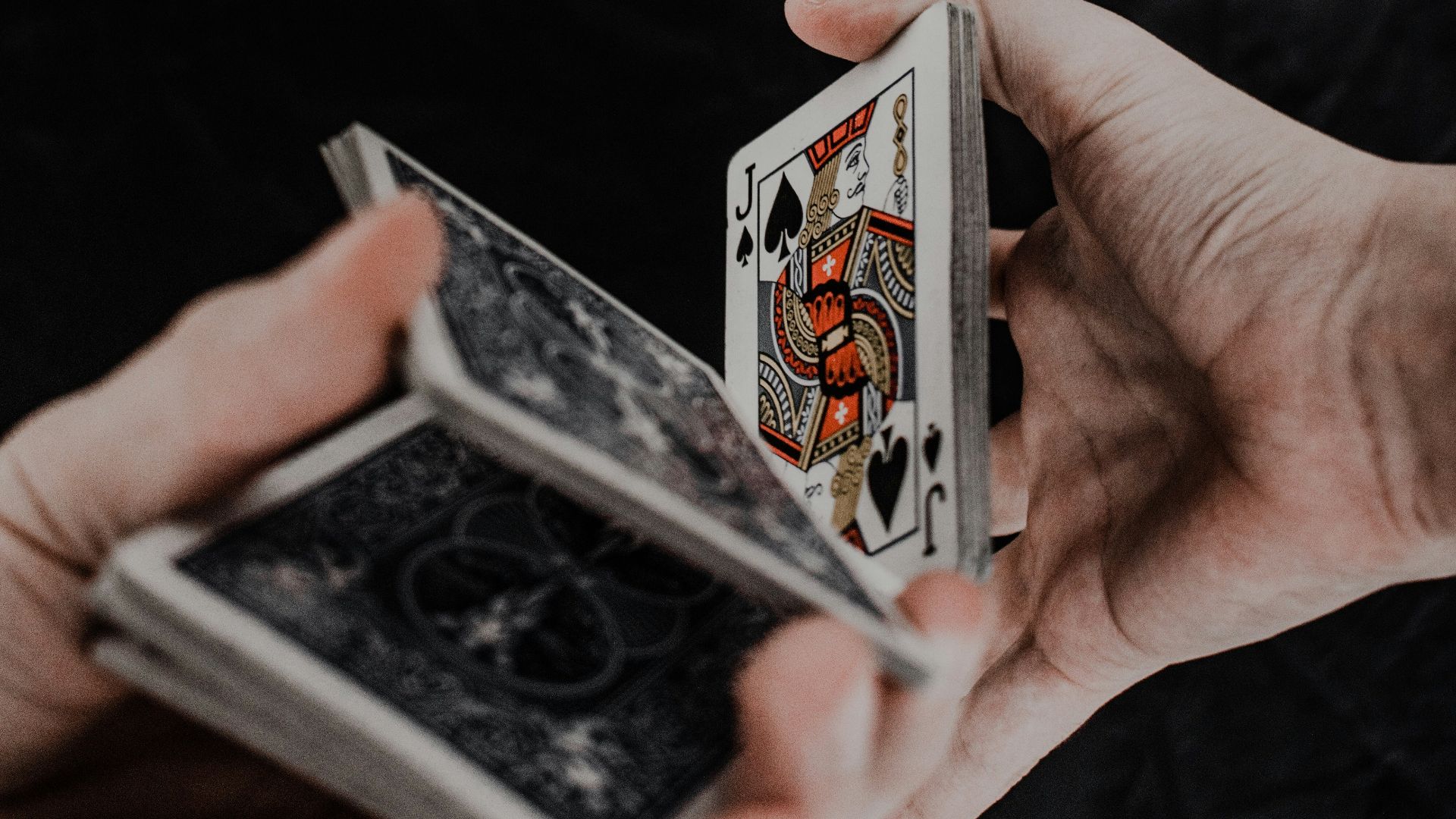 person holding playing cards on black textile