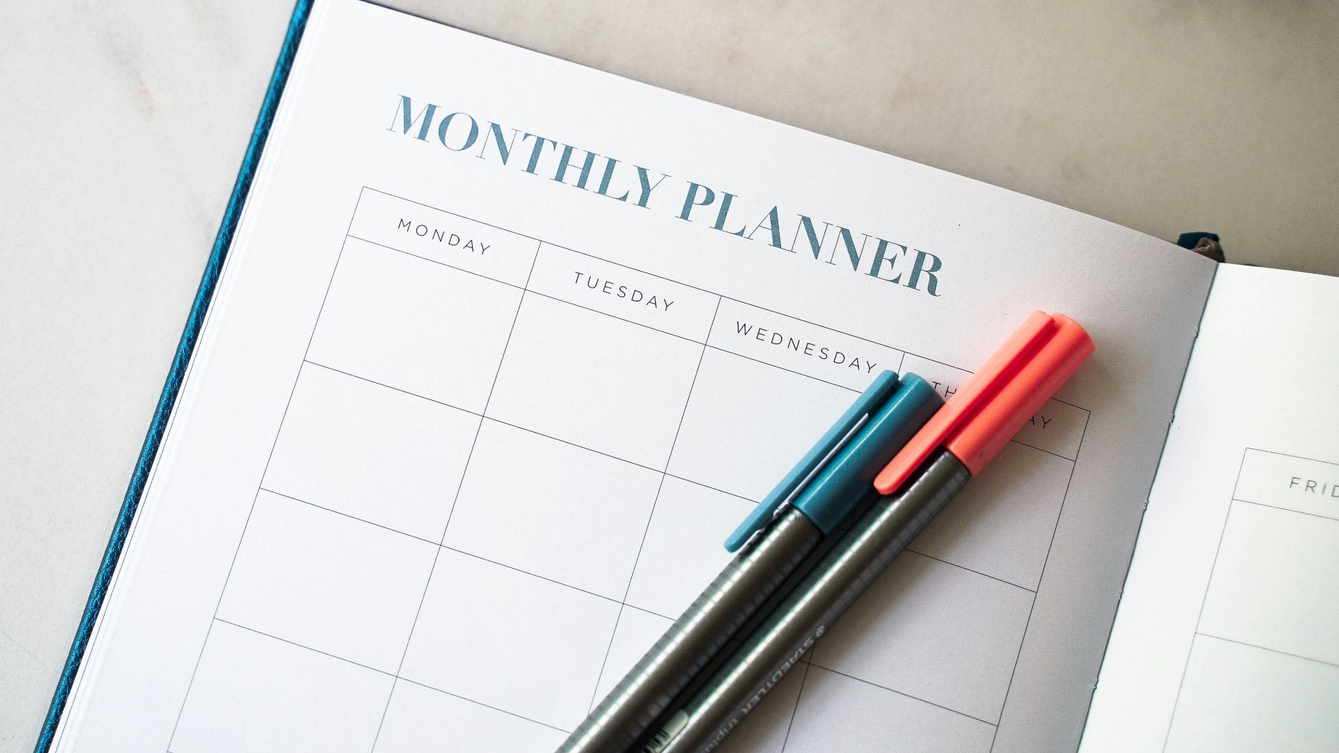 a planner with two pens sitting on top of it