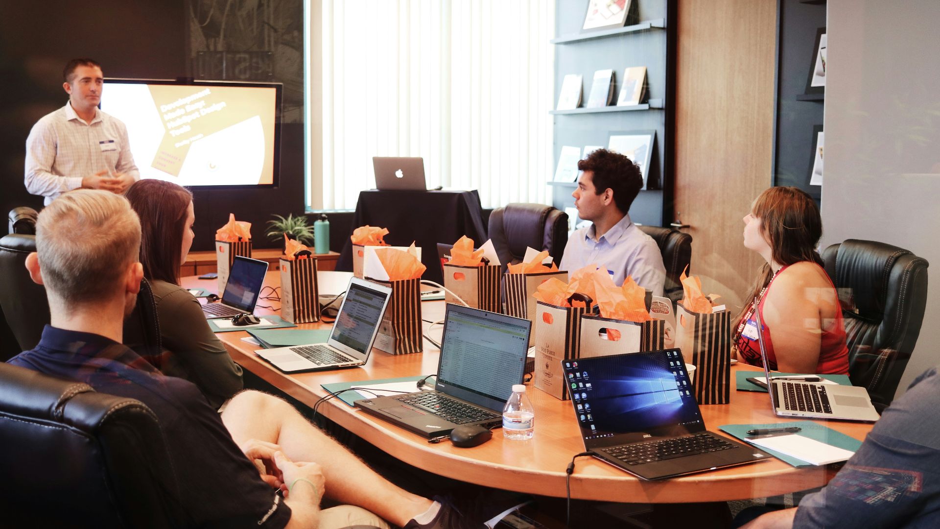 man standing in front of people sitting beside table with laptop computers