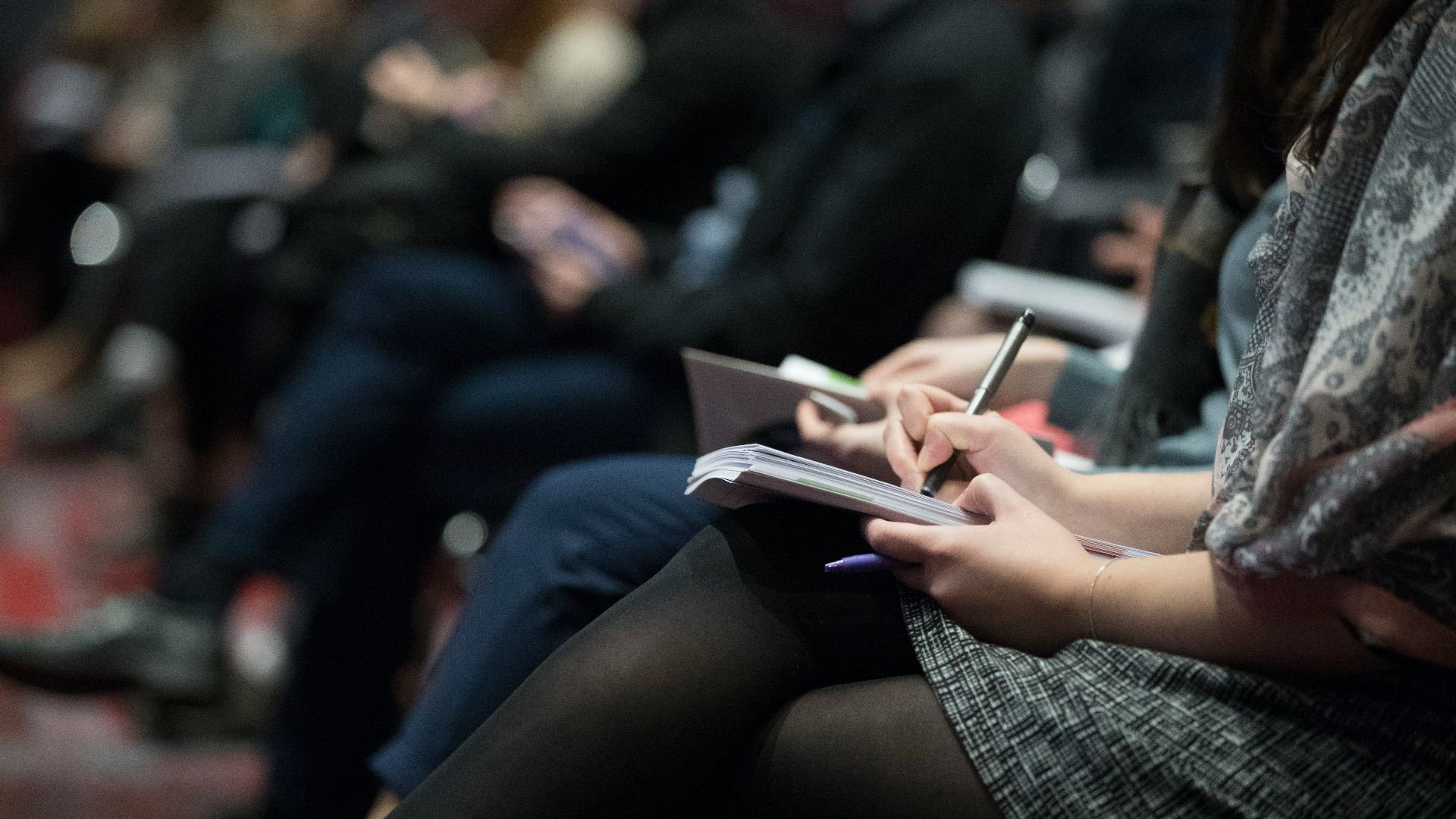 selective focus photography of people sitting on chairs while writing on notebooks