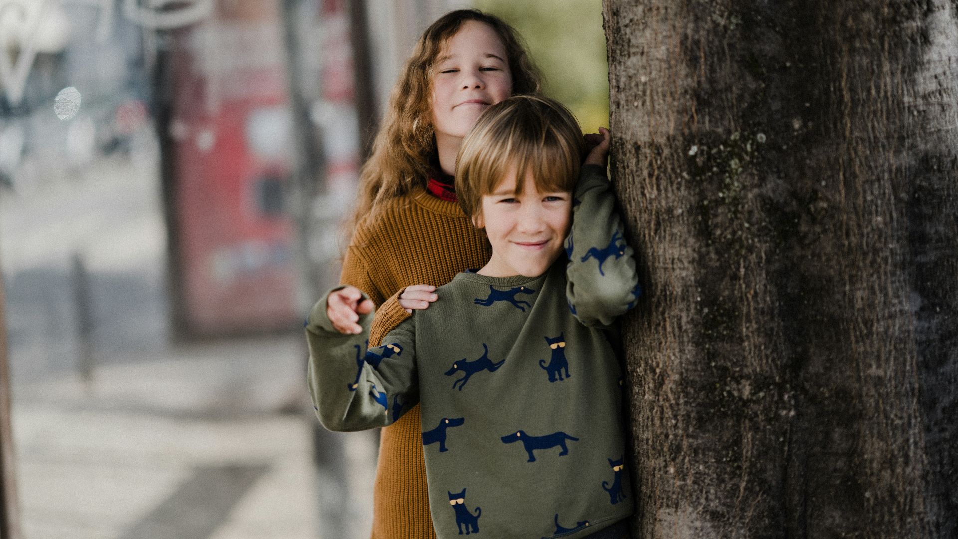 two young children hugging each other on a sidewalk