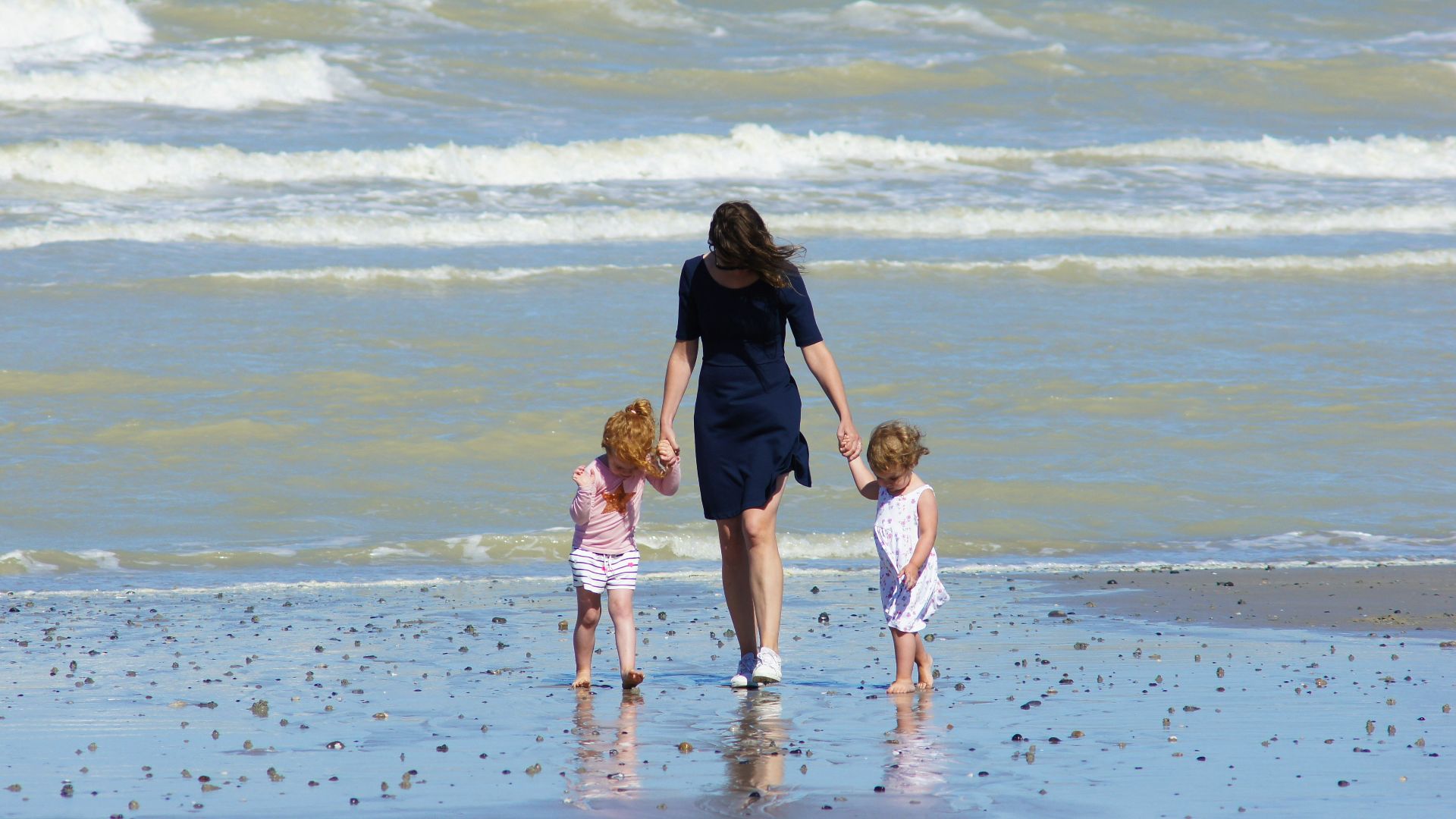 woman with 2 children walking on beach