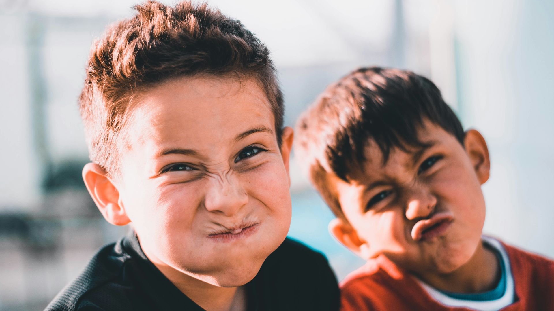 shallow focus photography of two boys doing wacky faces