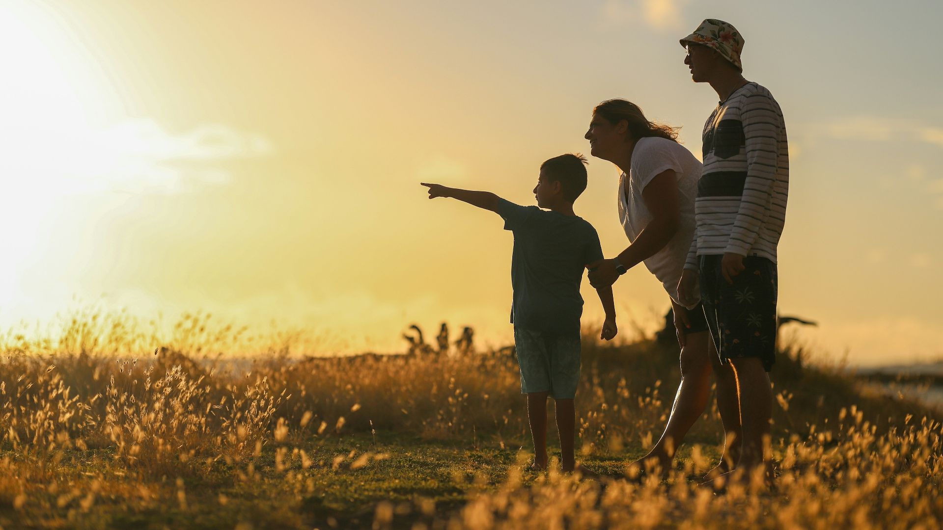 man and woman holding hands while walking on grass field during sunset