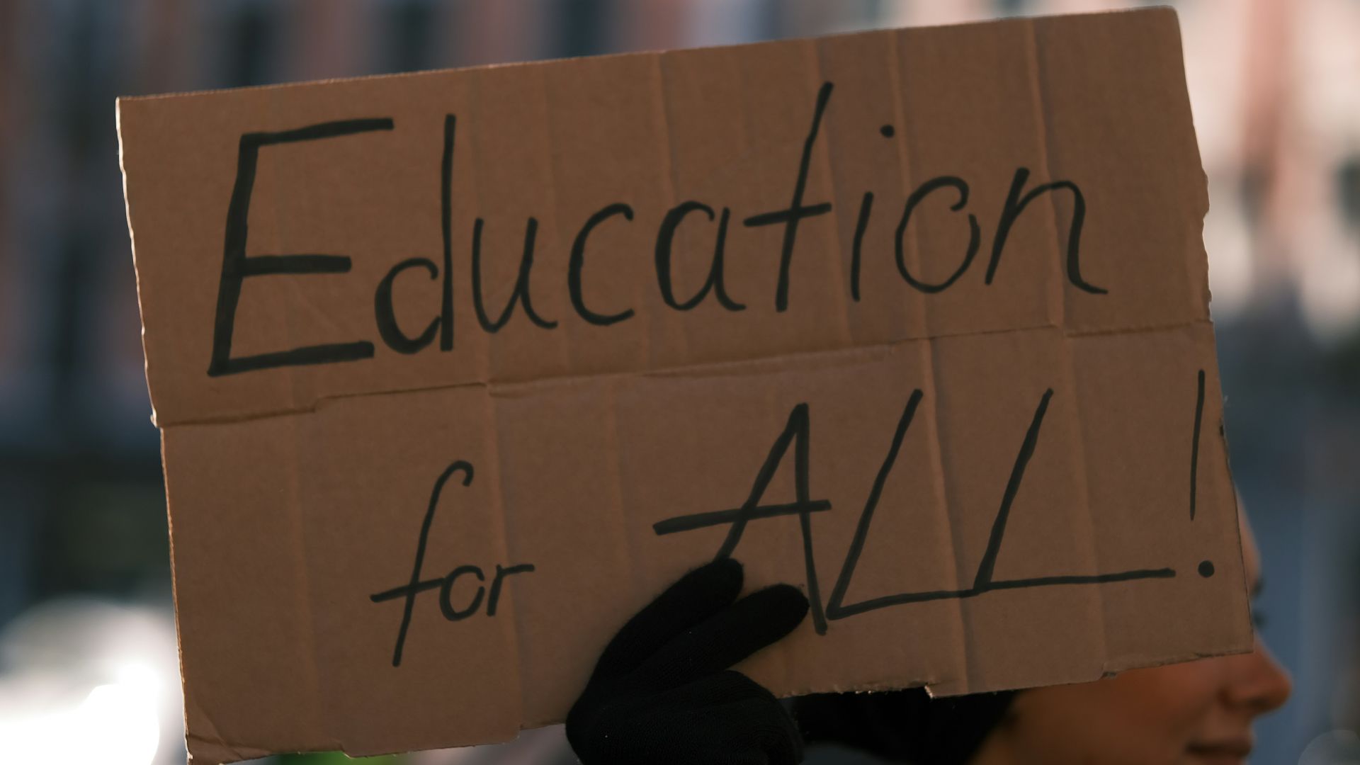 a person holding a sign that says education for all