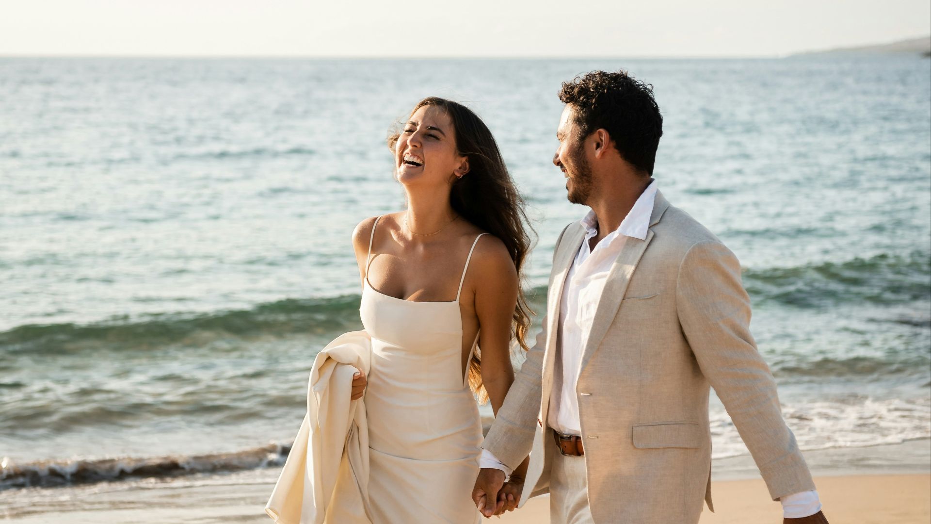 Newlyweds happily run along the beach.