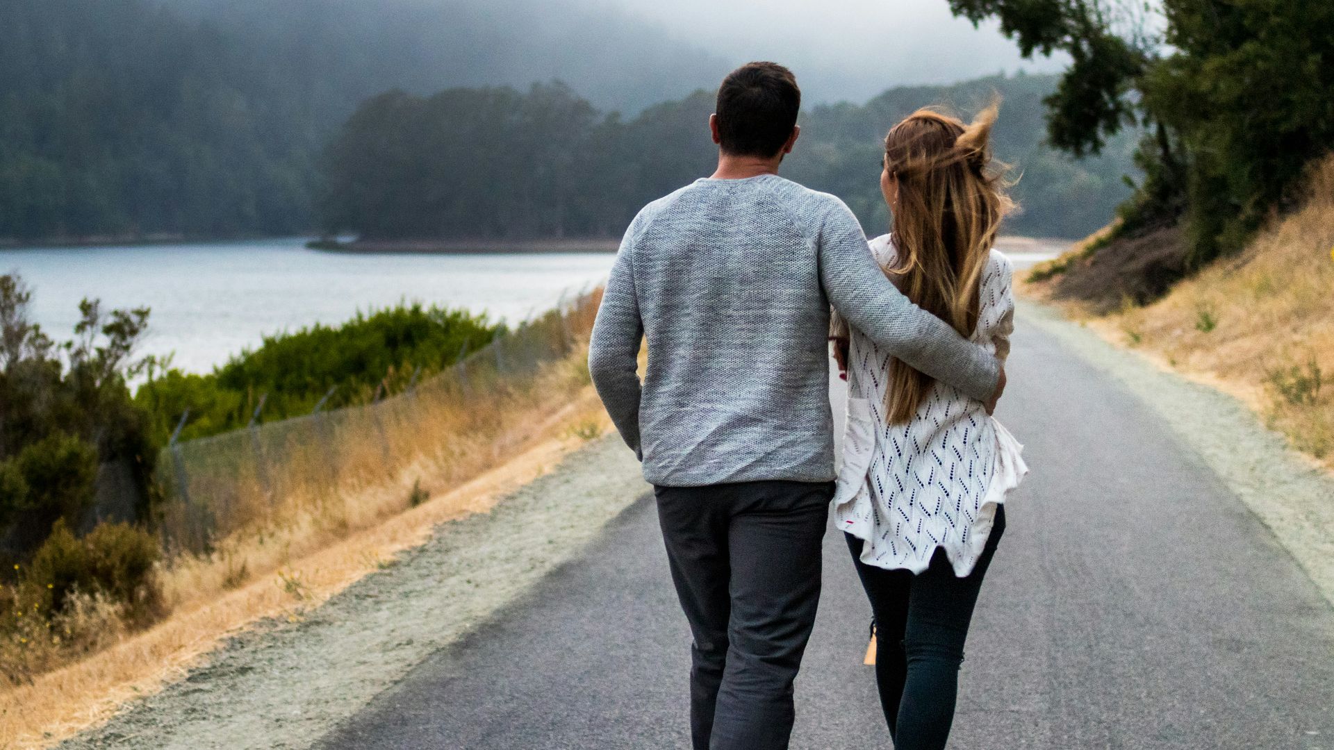 man and woman walking on asphalt road