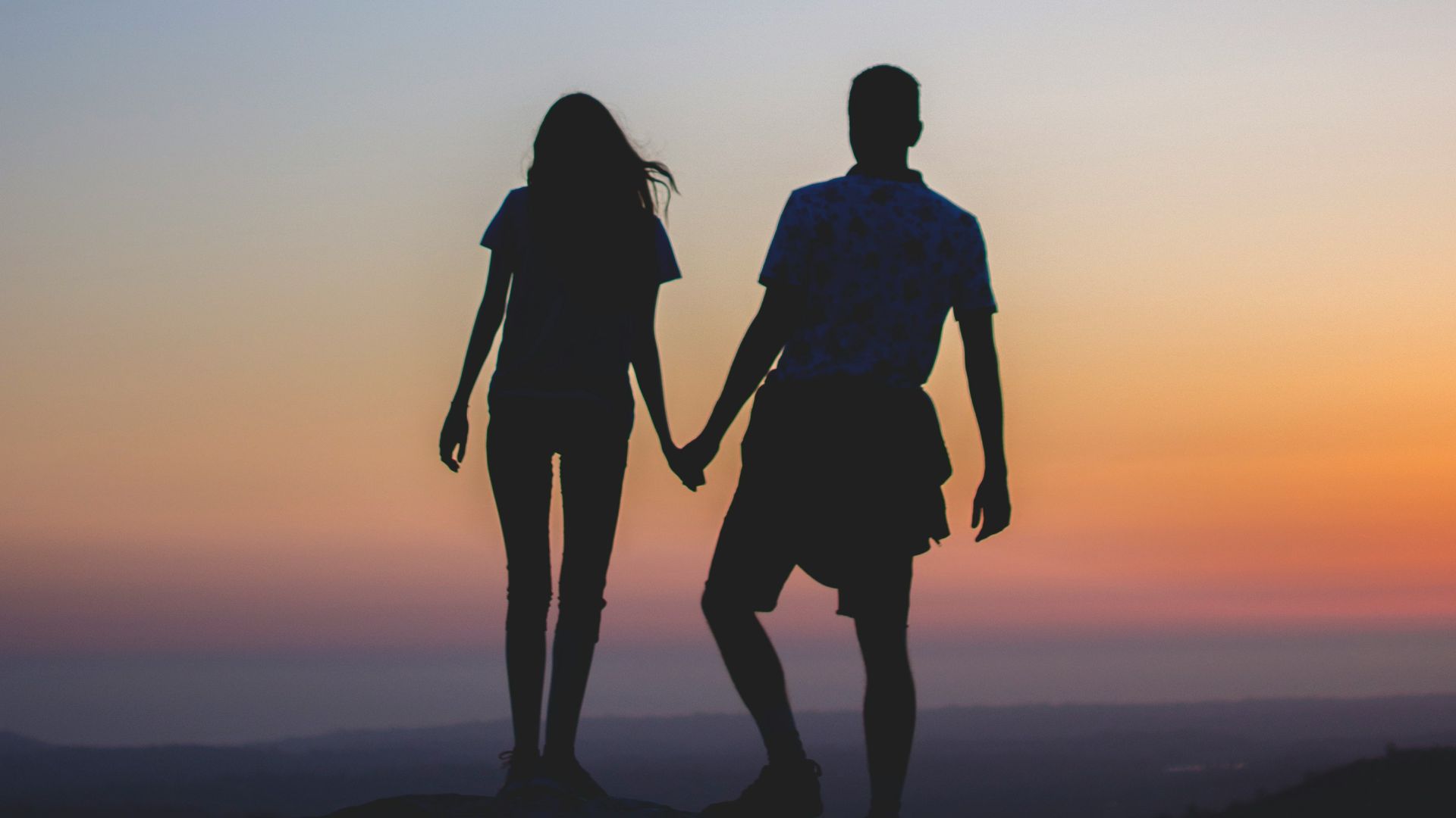 man and woman holding hands in silhouette photography