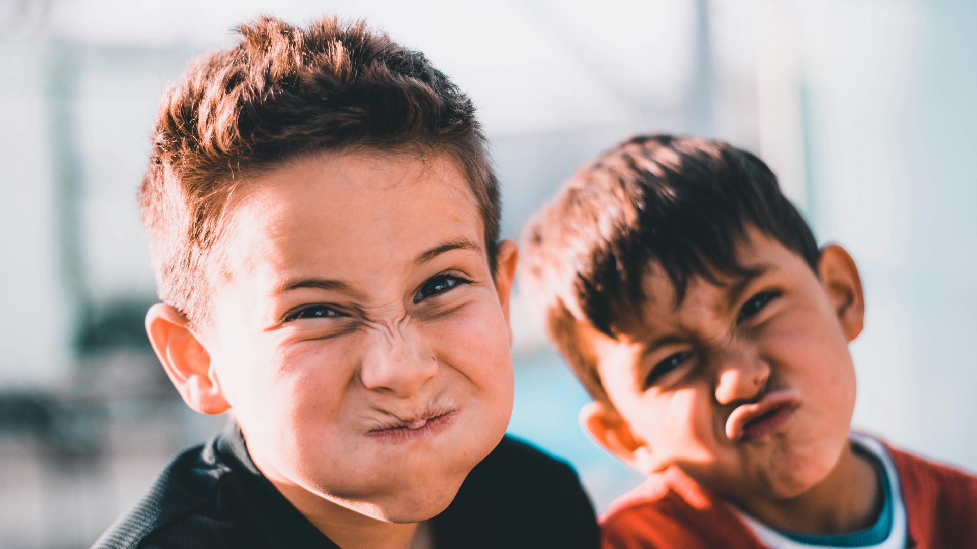 shallow focus photography of two boys doing wacky faces