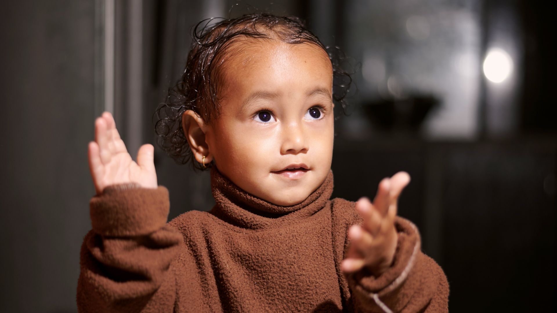 a little girl standing in a room with her hands in the air
