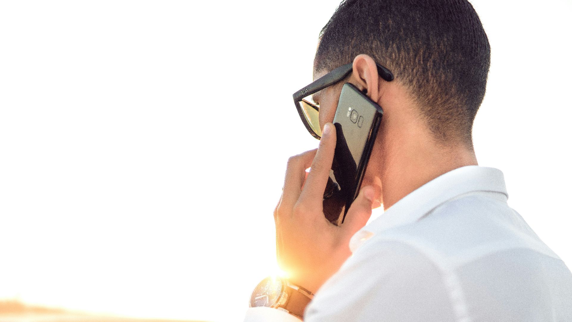 man holding smartphone standing in front of calm body of water