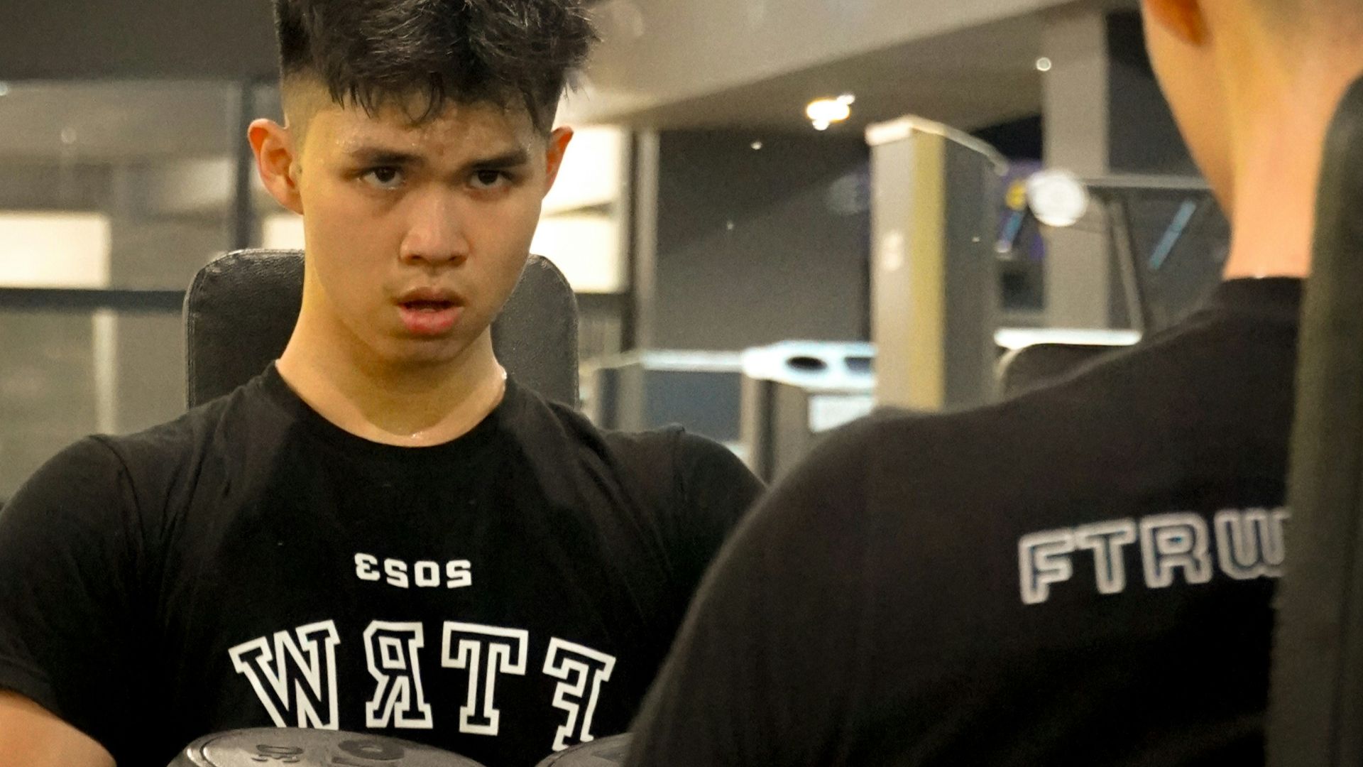 a man holding a dumbbell while standing next to another man