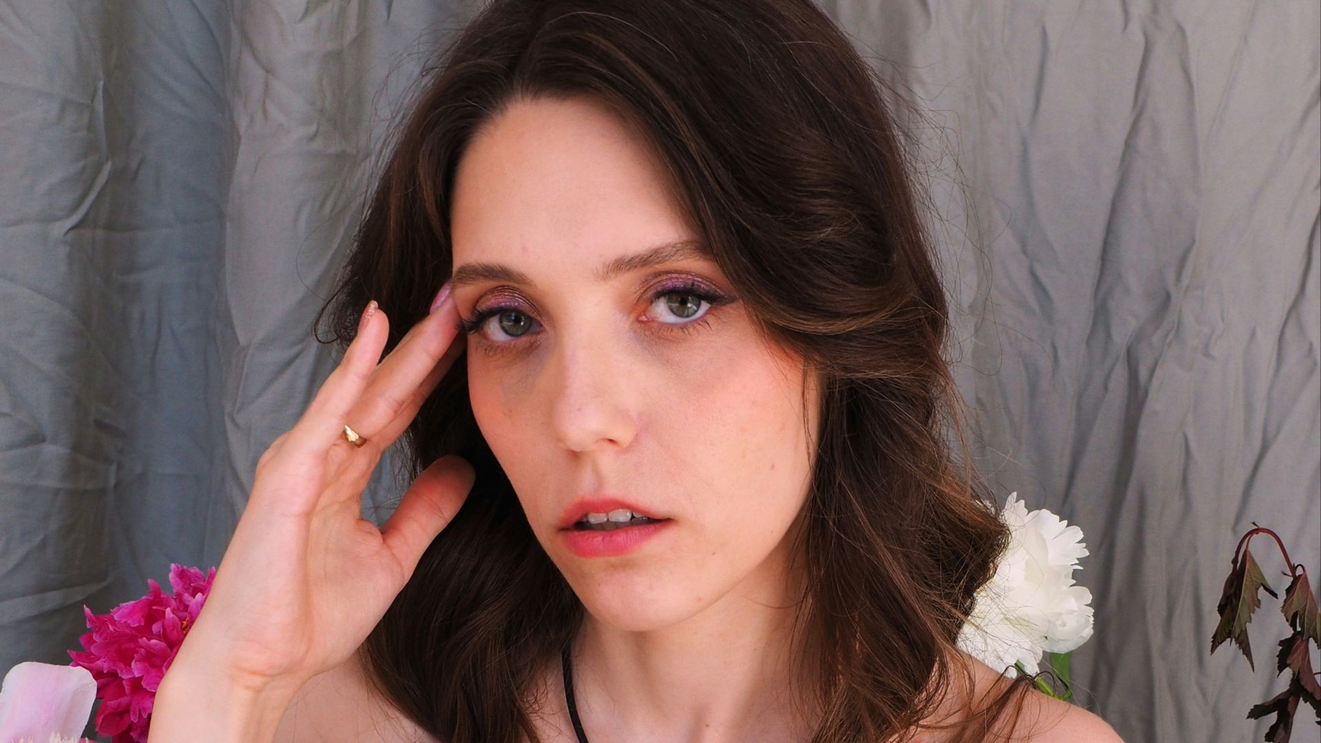 A woman in a blue dress holding her hand up to her face