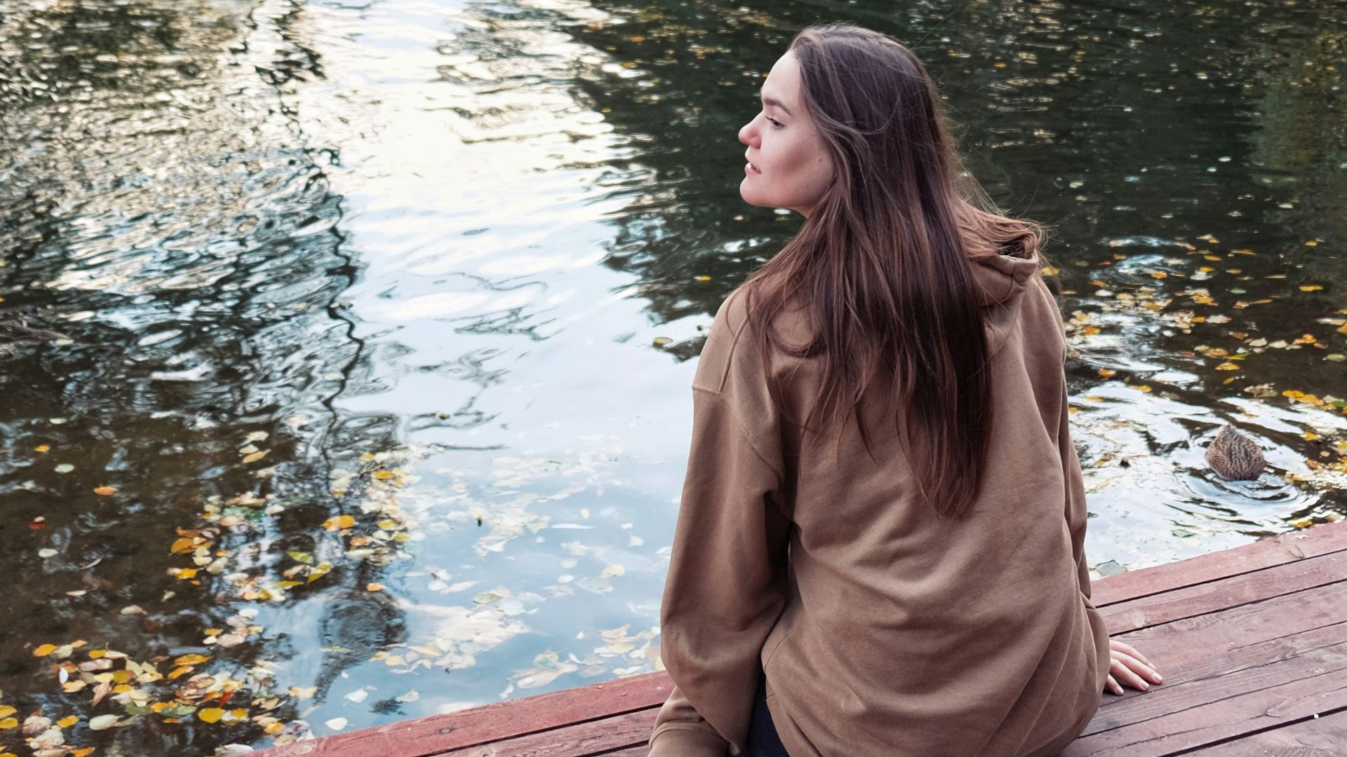 a woman sitting on a bench in front of a lake
