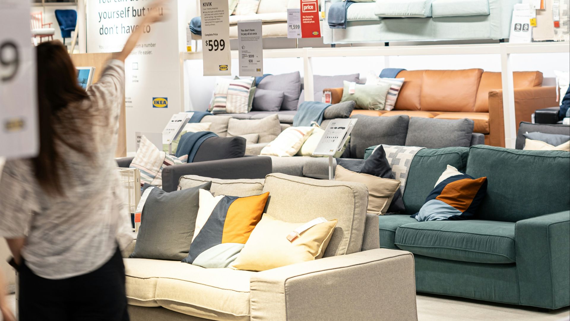 a woman holding a sign in a furniture store